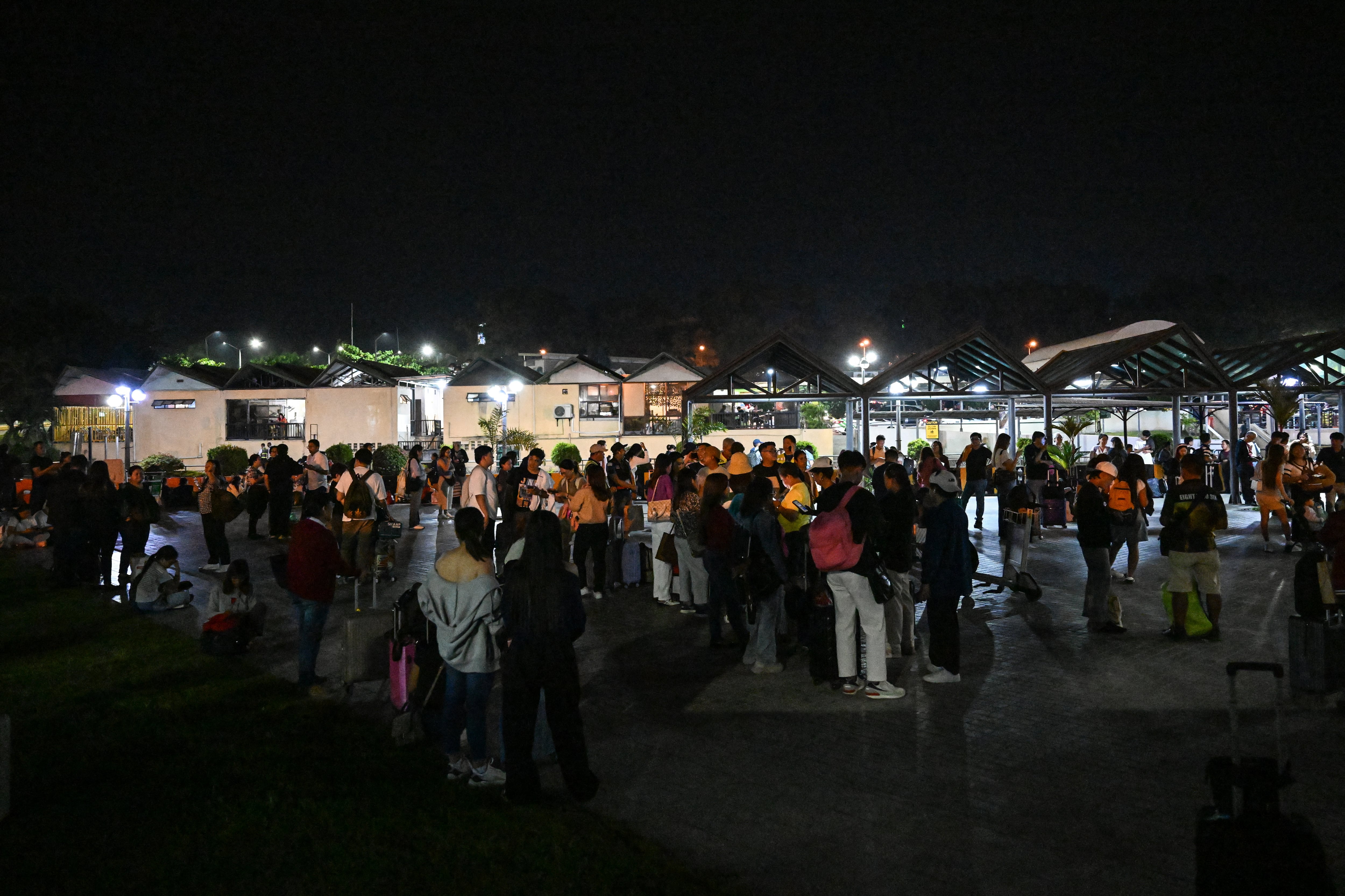 Gente salió a la intemperie mientras esperaba la autorización del personal del aeropuerto para entrar en la ciudad de Davao este 10 de octubre de 2025, tras una réplica del terremoto anterior. Dos potentes terremotos azotaron el sur de Filipinas el 10 de octubre, causando la muerte de al menos 8 personas y activando dos alertas de tsunami. Fotografía: