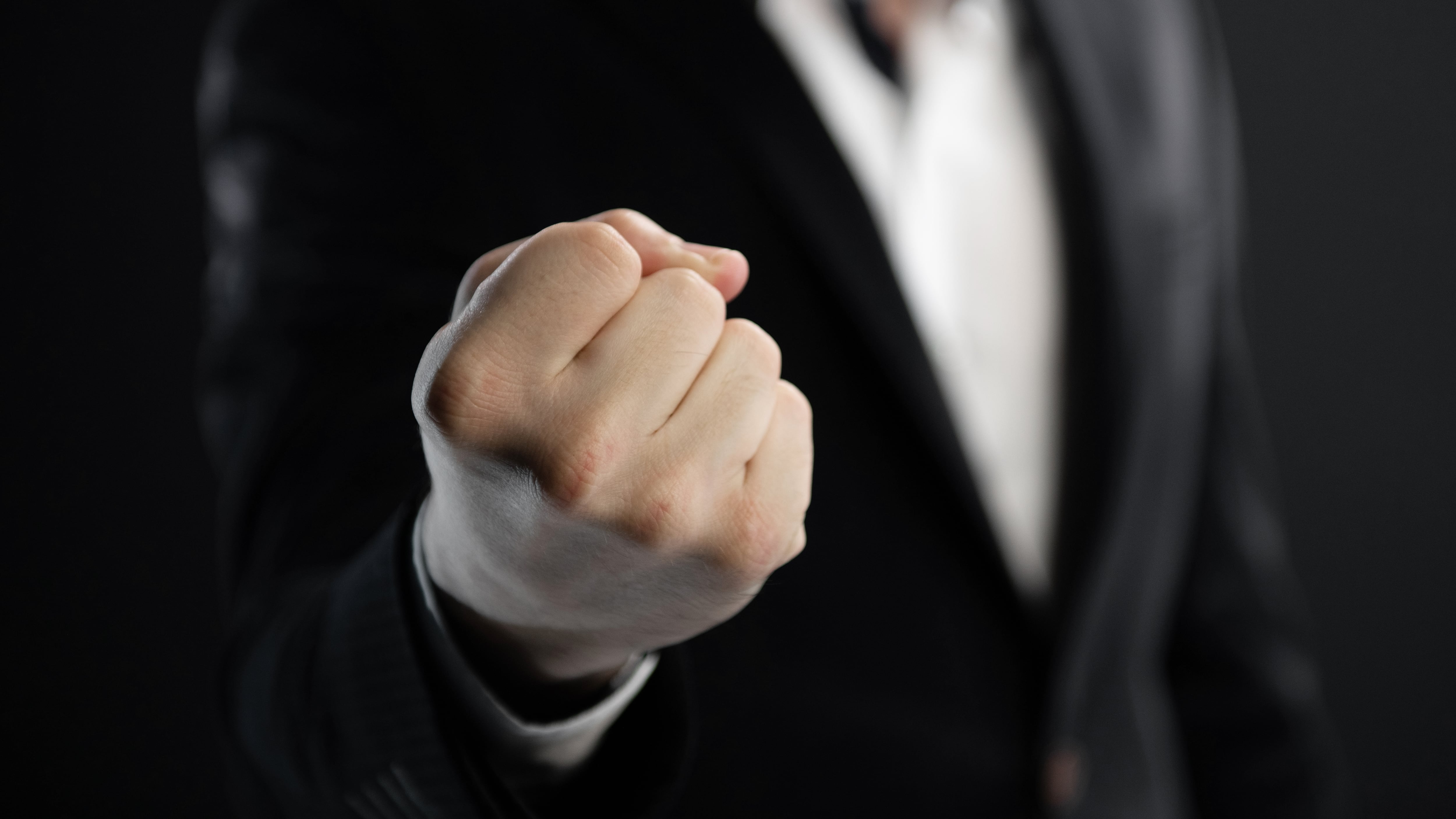 Puño apretado en primer plano, hombre con traje