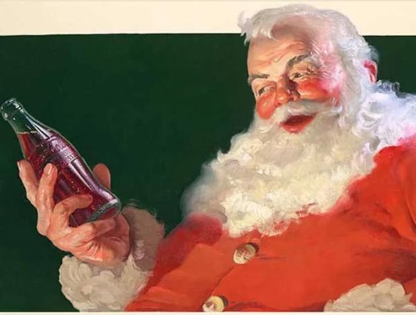 Santa Claus sonriente sosteniendo una botella de Coca-Cola, ilustrado por Haddon Sundblom, destacando el diseño que popularizó la imagen moderna de este ícono navideño.
