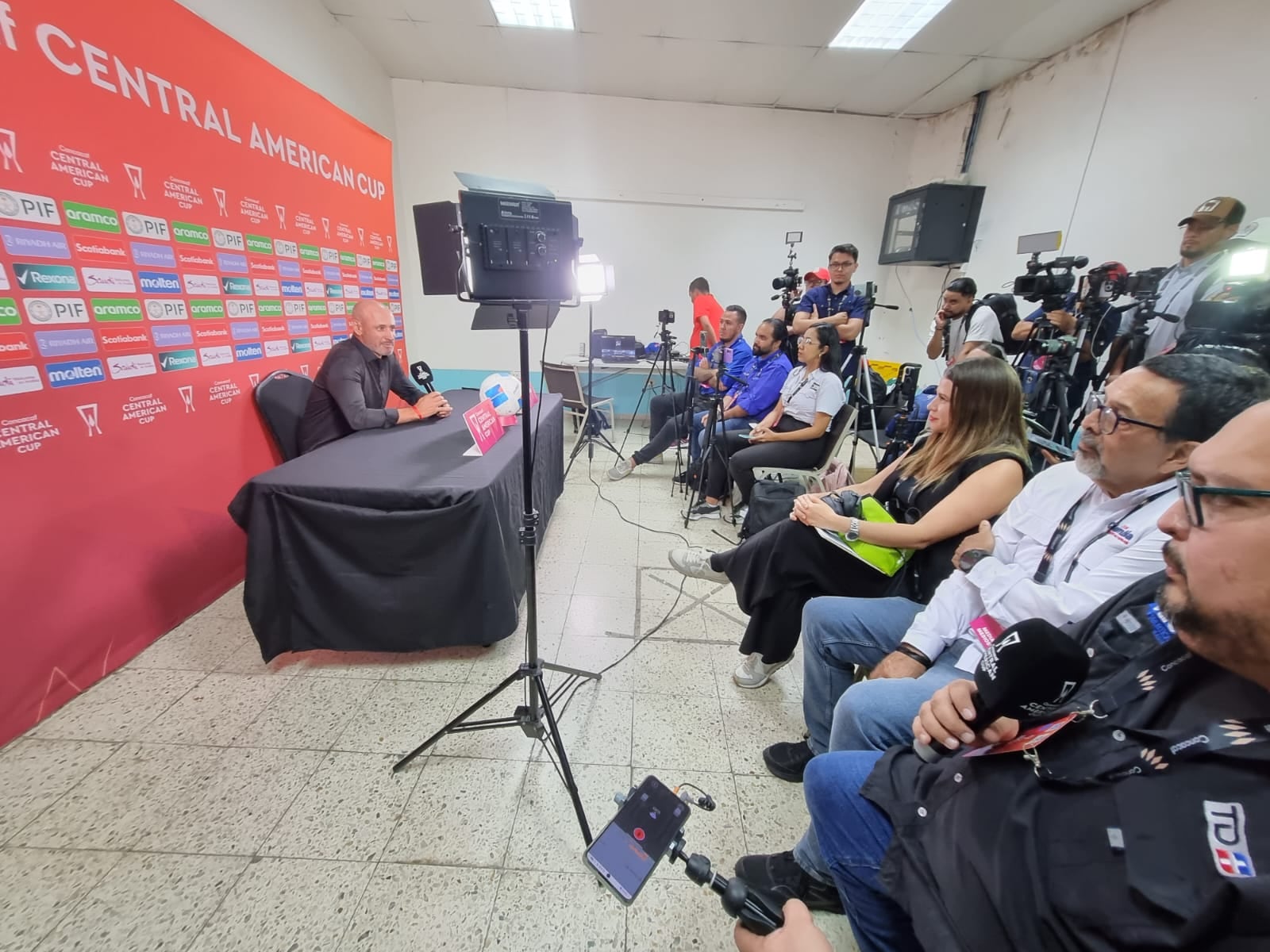 El comunicador Rodolfo Médez (camisa blanca), junto a su hijo, Adrián Méndez, escucha con atención al técnico de Olimpia, Eduardo Espinel.