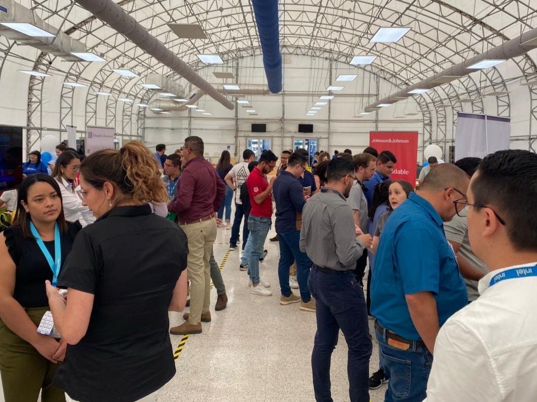 Personas conversan y comparten información laboral durante una feria de empleo dirigida a colaboradores cesados de Intel, organizada por entidades gubernamentales y empresas de manufactura e industria médica.