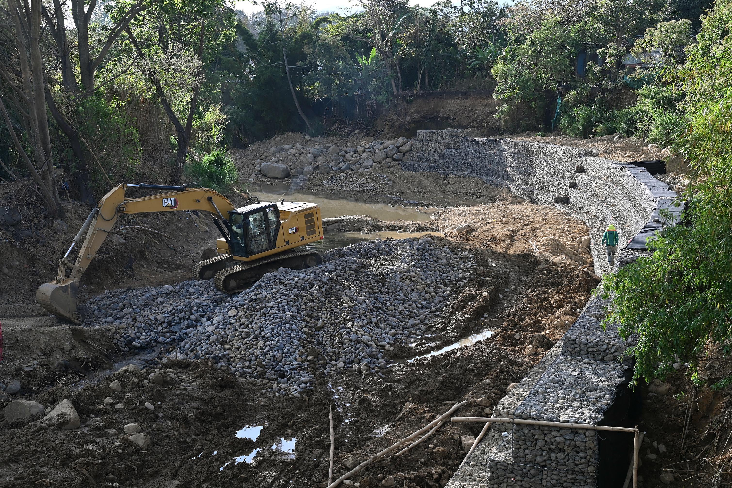 04 de abril del 2025. San Rafael Arriba de Desamparados. Río Cañas. 06:00 hrs. Maquinaria y personal de una empresa constructora privada realizan la construcción de varios muros de retención (gaviones) a lo largo del río Cañas al sur de la capital. La obra es financiada por el BCIE (Banco Centroamericano de Integración Económica) y gestionada por la Comisión Nacional de Emergencias. El proyecto beneficiaría a unas 24000 personas de comunidades como Calle Robles, San Bosco, Blanca Durán y La Granja que sufrieron serios daños con las lluvias del año anterior. Algunos vecinos del lugar externaron su molestia pues consideran que se refuerzan orillas del cauce del río pero se debilitan otras. En la foto: maquinaria pesada y personal de una constructora privada realizan las labores en el río Cañas. Foto: Albert Marín para la Nación.