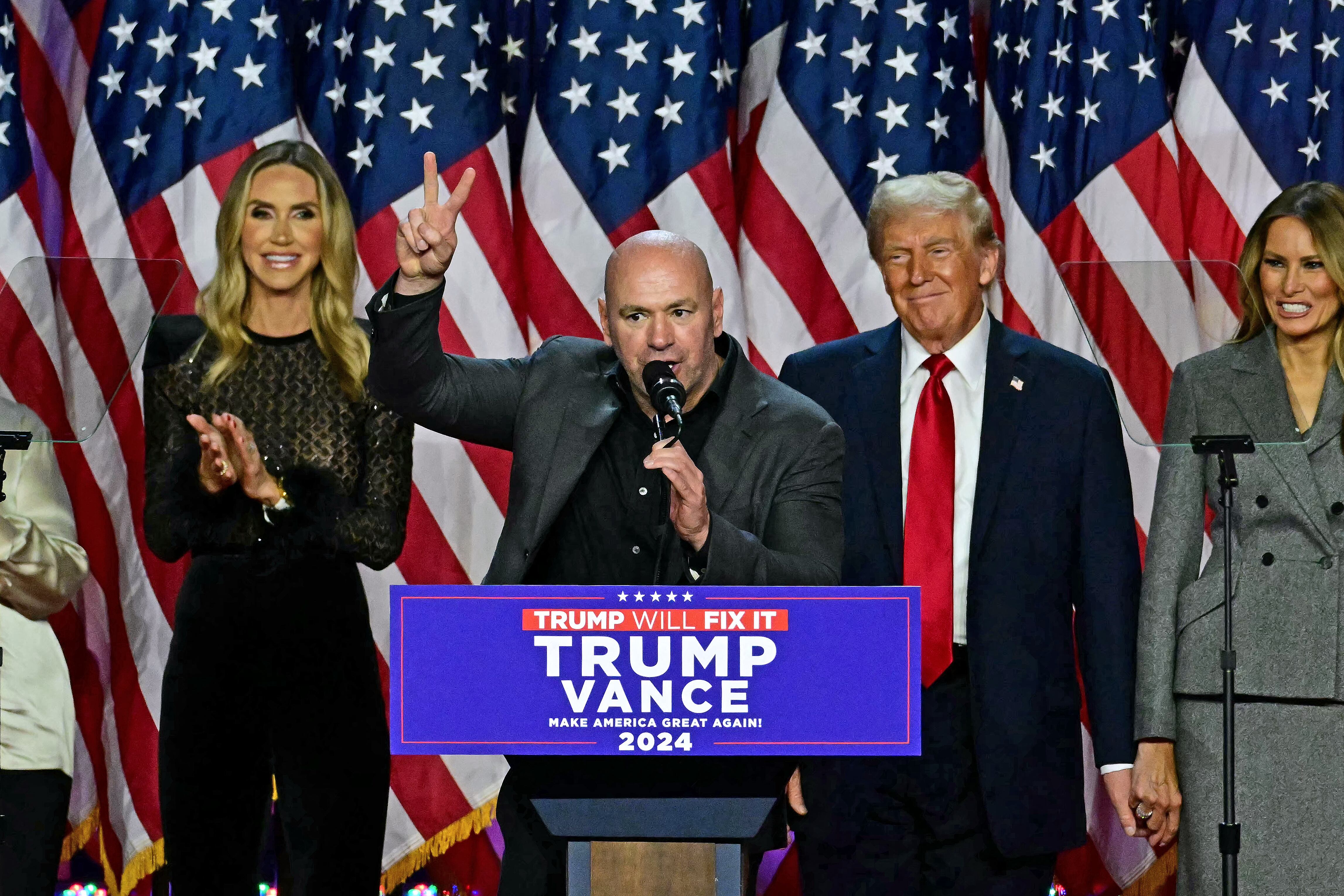 Dana White, presidente de la UFC, en un discurso junto a Donald Trump y Melania Trump en un evento político, con banderas de Estados Unidos al fondo.