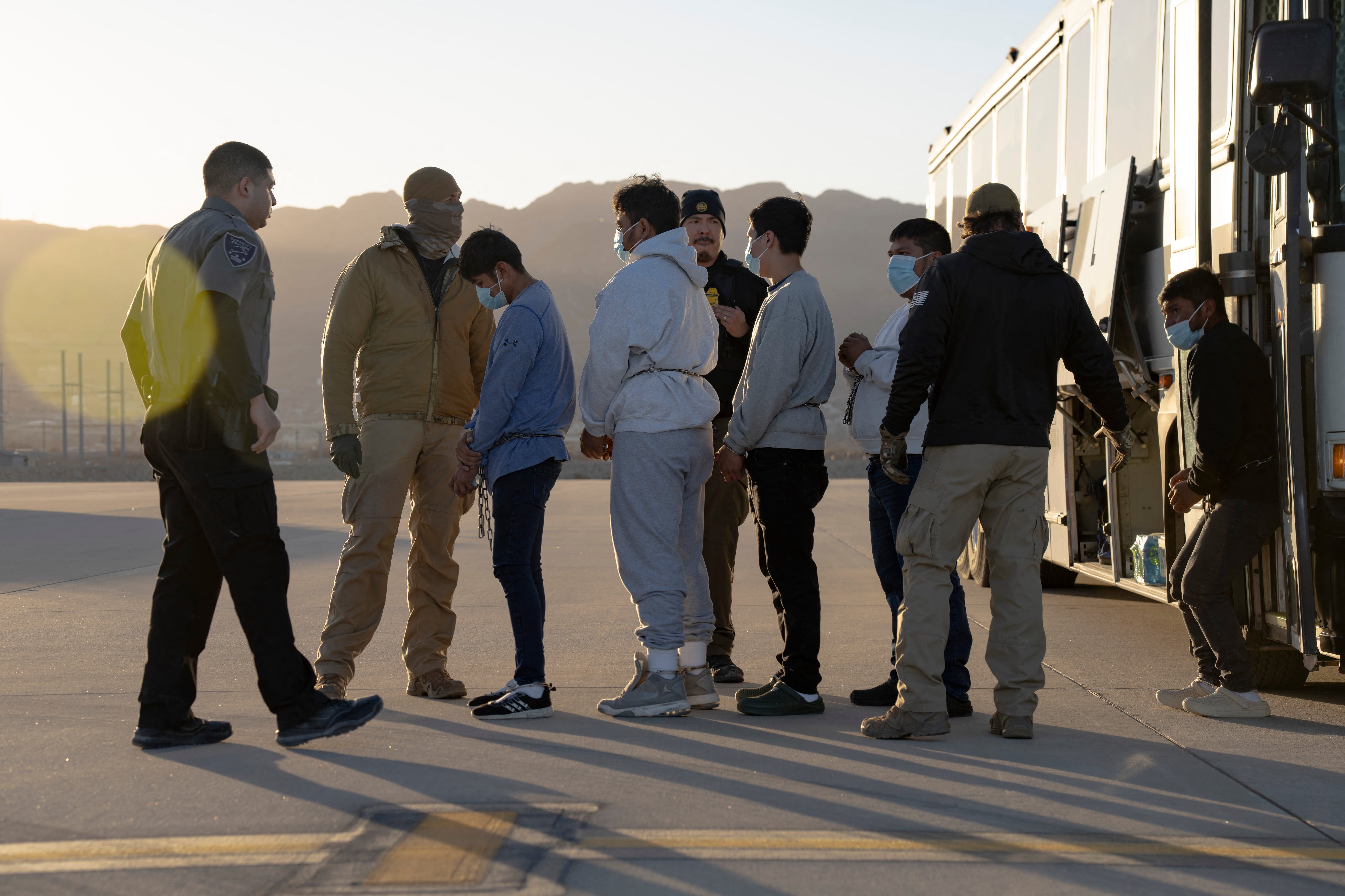 Esta imagen publicada por el Departamento de Defensa muestra a agentes de Aduanas y Protección Fronteriza de EE. UU. guiando a inmigrantes indocumentados para abordar un vuelo de deportación en Fort Bliss, Texas.