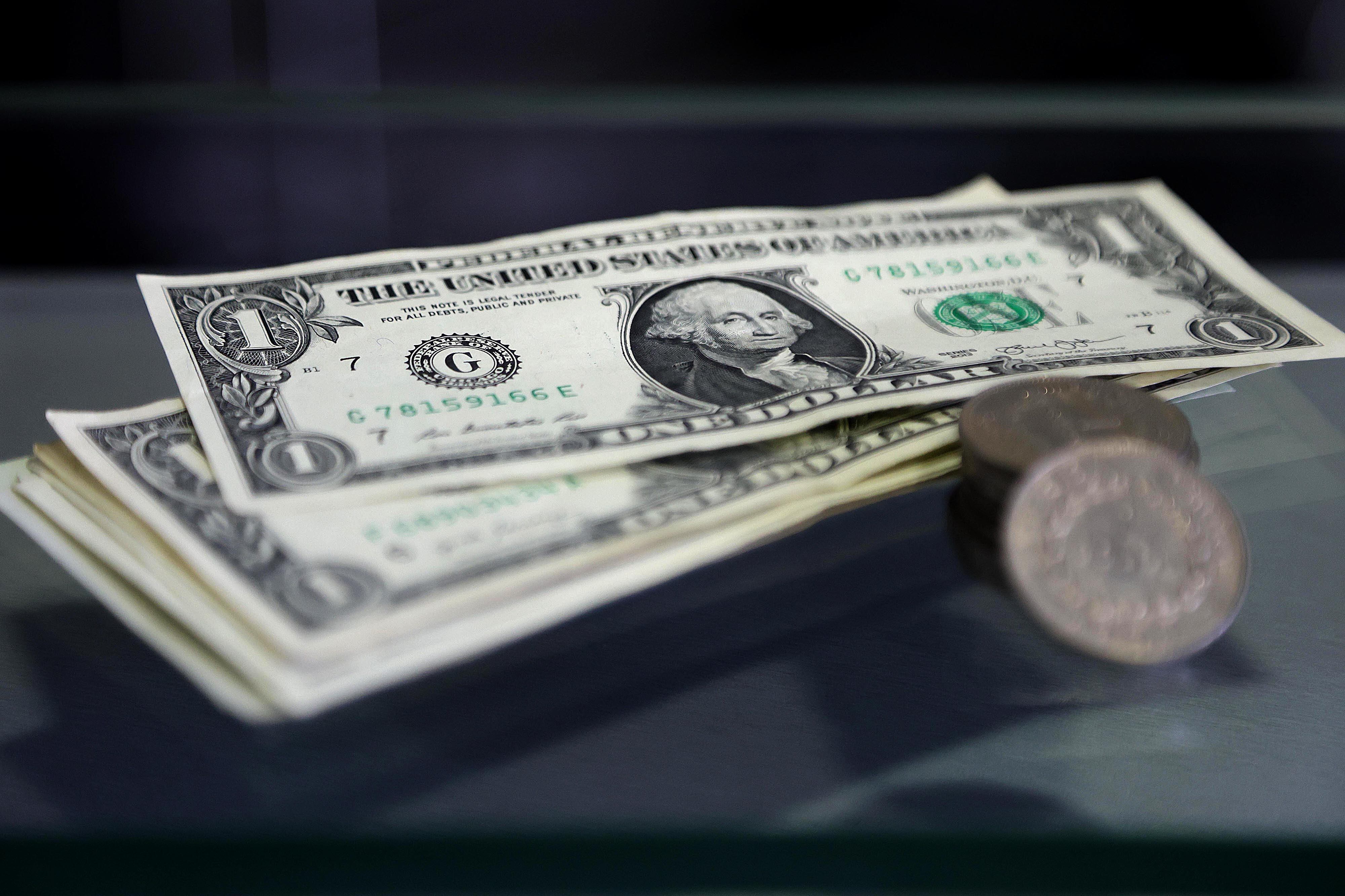 Un primer plano de billetes de dólar estadounidenses y monedas apiladas, representando las fluctuaciones en el tipo de cambio del dólar en Costa Rica al cierre de la primera semana de 2025.