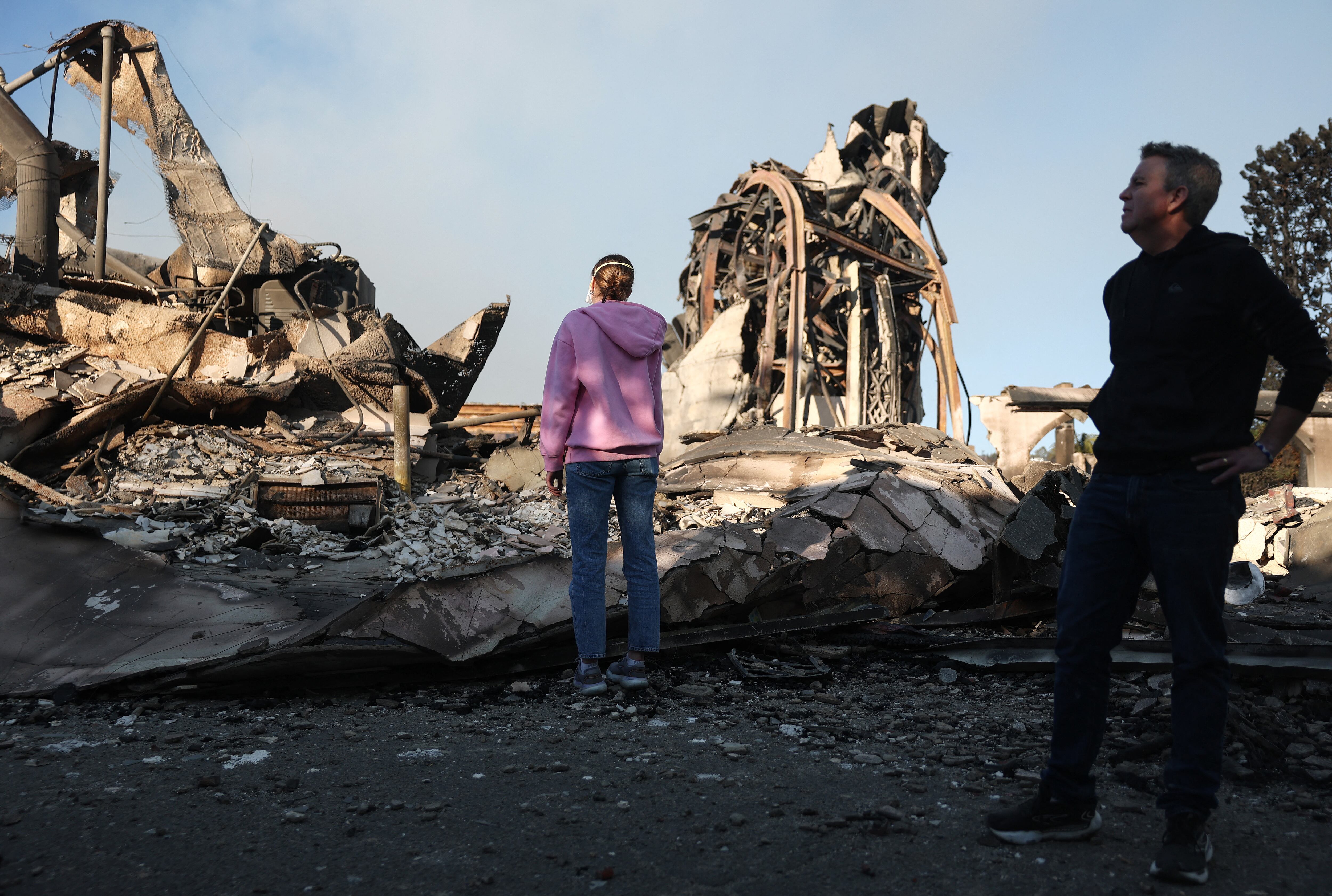 El reverendo John Shaver (derecha) observa mientras visita los restos de la Iglesia Metodista Unida Comunitaria, donde es pastor, mientras los incendios forestales causan daños y pérdidas en el condado de Los Ángeles en Pacific Palisades, California.