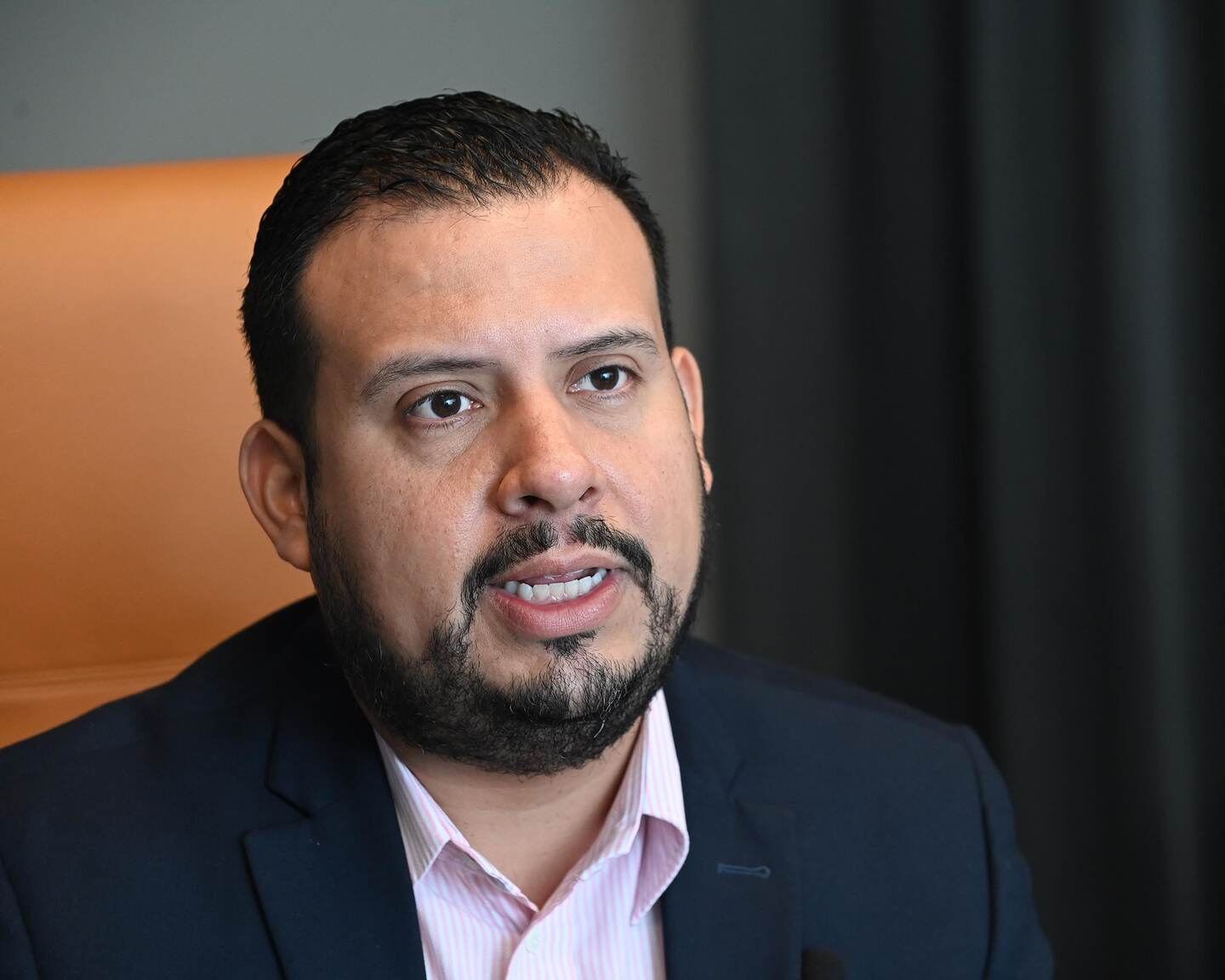 Primer plano de Manuel Rodríguez Arce, de la CCSS. Al fondo, respaldar anaranjado de la silla. Es un hombre de cara redonda, con barba en forma de candado. Viste saco oscuro y camisa clara.