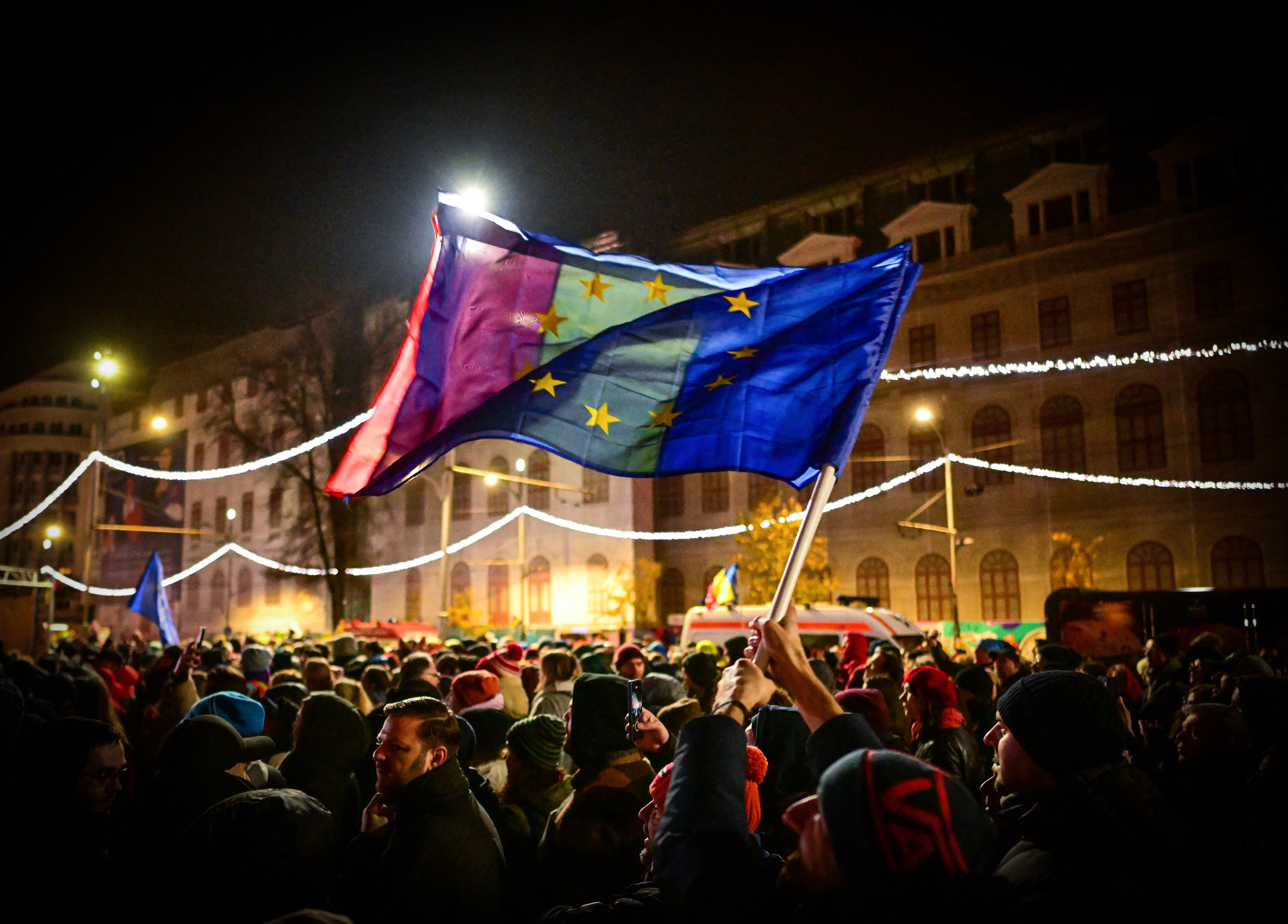 Manifestantes en Bucarest ondean banderas de la Unión Europea y Rumania durante una marcha proeuropea en la Plaza de la Universidad, diciembre de 2024.