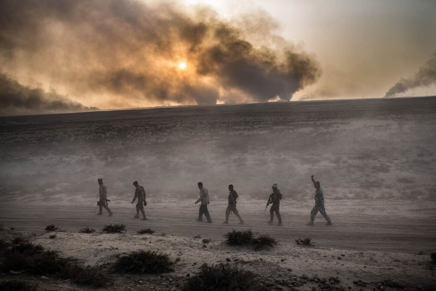 Soldados iraquíes pasan por una carretera mientras el humo sale del área de Qayyarah, unos 60 kilómetros al sur de Mosul, durante una operación, este miércoles 19, contra el grupo terrorista Estado Islámico.