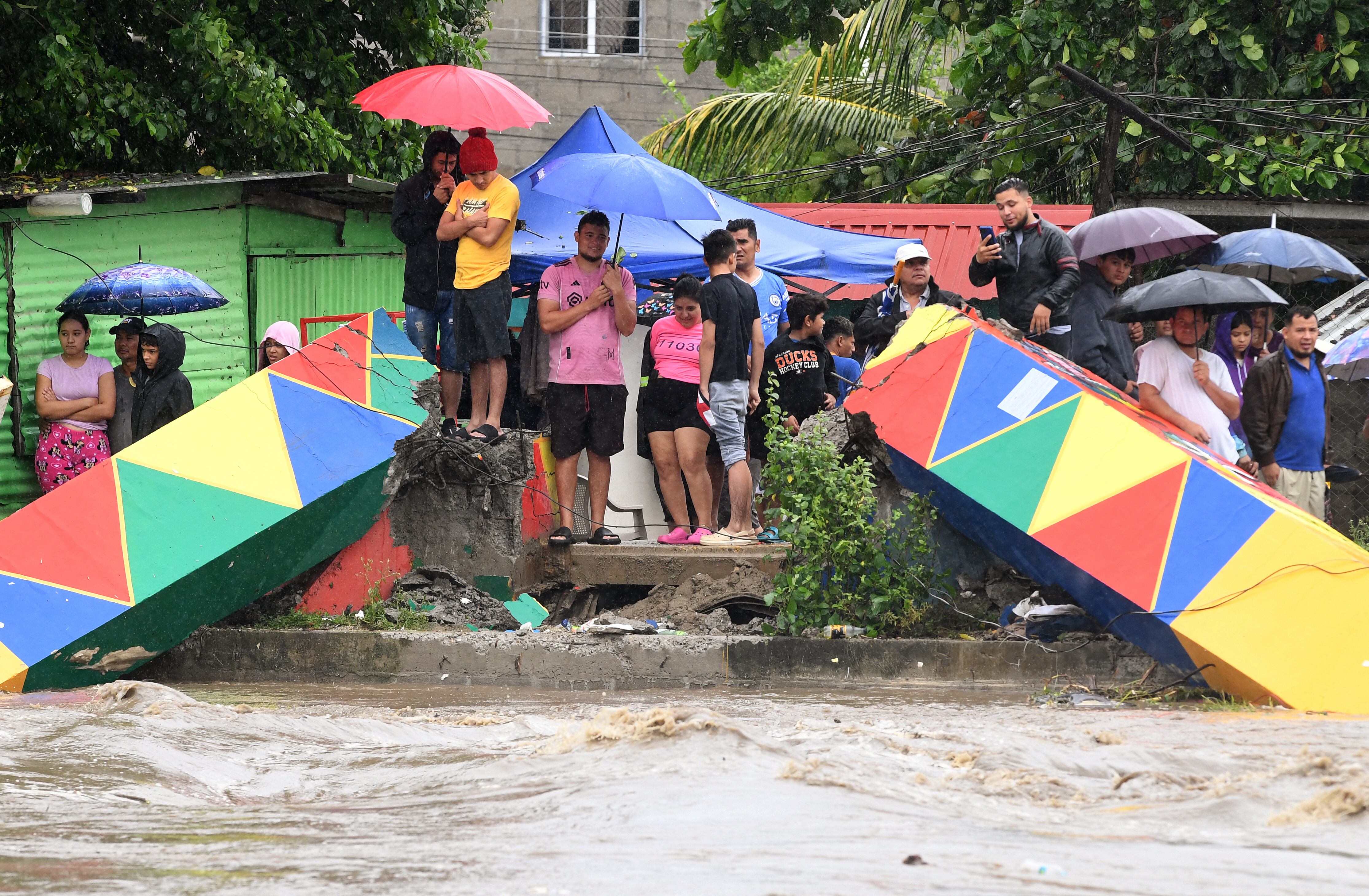 Personas observan el puente Hamaca destruido por la crecida del río Bermejo en San Pedro Sula, Honduras, debido a las fuertes lluvias que dejó la tormenta tropical Sara. Una persona murió y cientos fueron afectados.