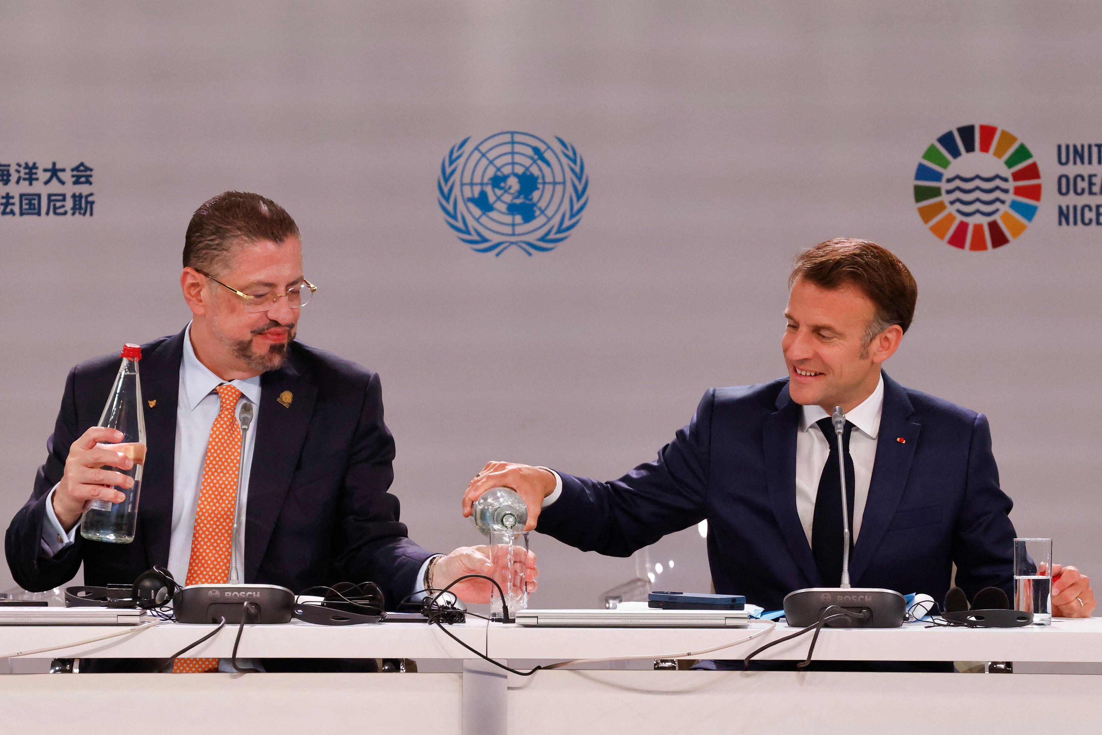 French president Emmanuel Macron (R) serves water to Costa Rica's President Rodrigo Chaves Robles as they attend the third United Nations Ocean Conference (UNOC3), which gathers leaders, resea