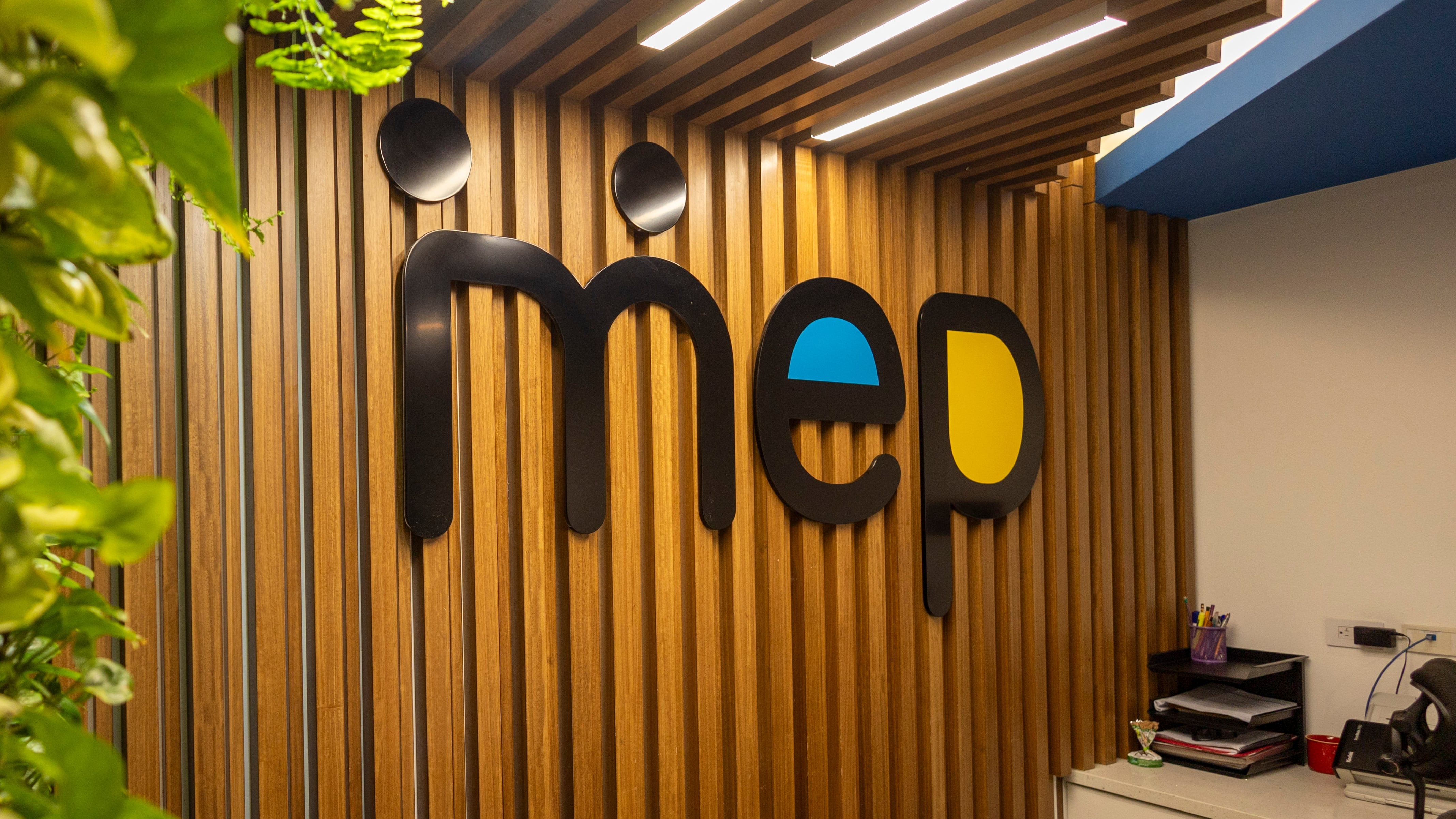 Logo del Ministerio de Educación Pública (MEP) en la pared principal de su sede central, acompañado de elementos decorativos naturales.