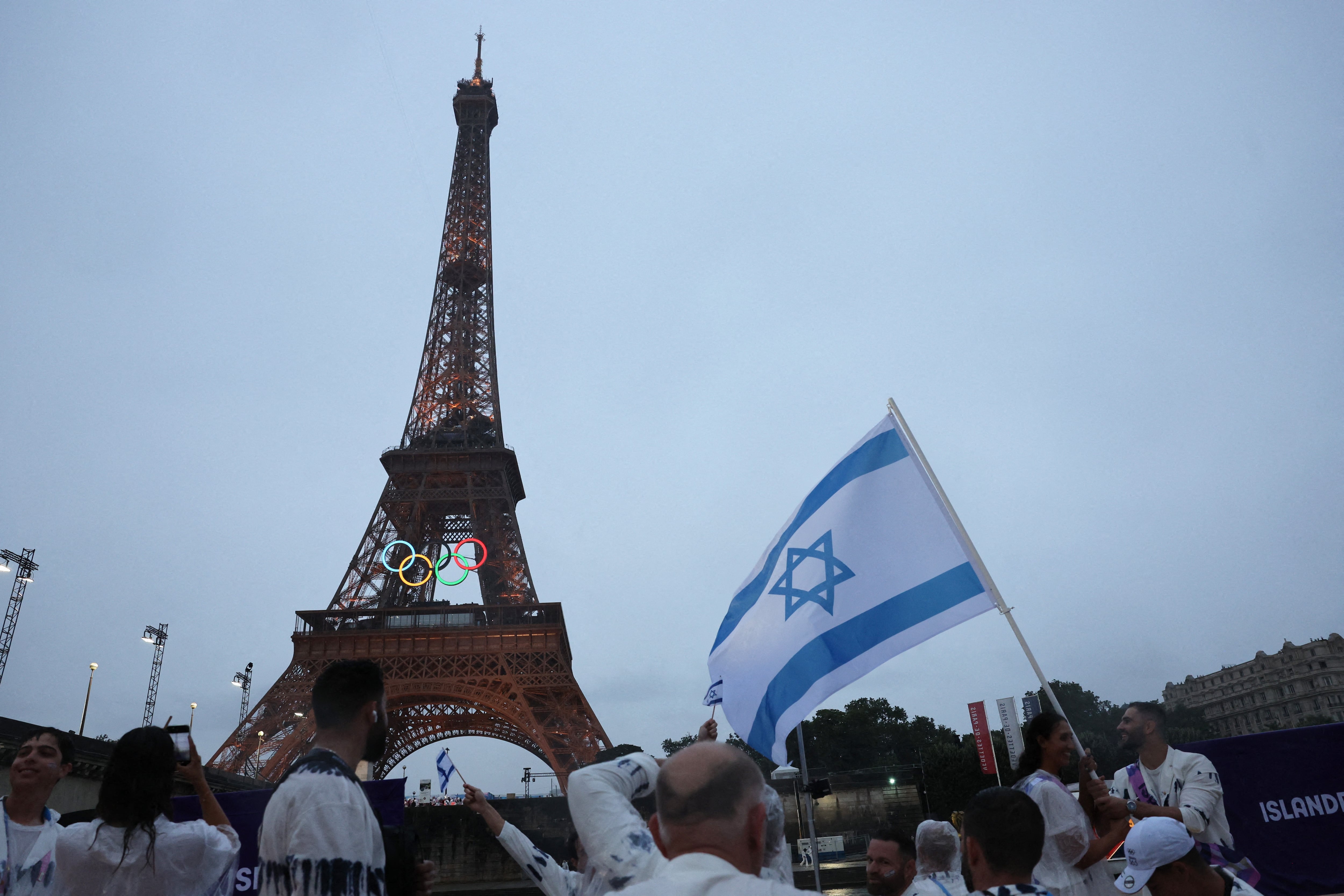 Atletas de Israel observan mientras la Torre Eiffel se ve desde a bordo de un bote en el desfile flotante en el río Sena durante la ceremonia de apertura.