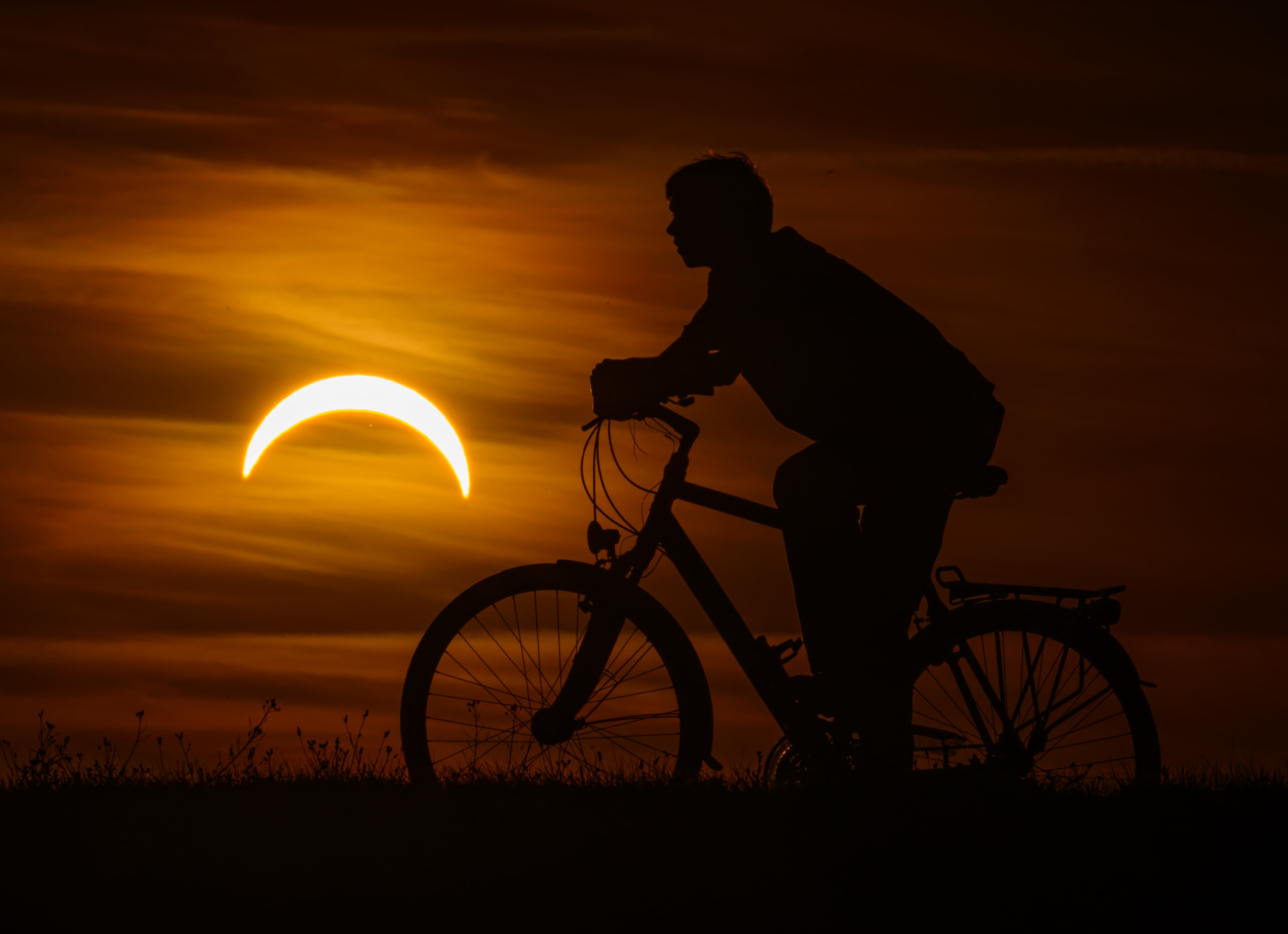 12 de agosto de 2026, Brandeburgo, Jacobsdorf: Un niño en bicicleta observa el eclipse solar parcial en el este de Brandeburgo. Según el Servicio Meteorológico Alemán, cuando el eclipse solar parcial sea visible sobre Alemania esta noche, las condiciones climáticas serán ideales para observarlo en casi todas partes a esa hora. Foto: Patrick Pleul/dpa (Foto de PATRICK PLEUL / dpa Picture-Alliance vía AFP)