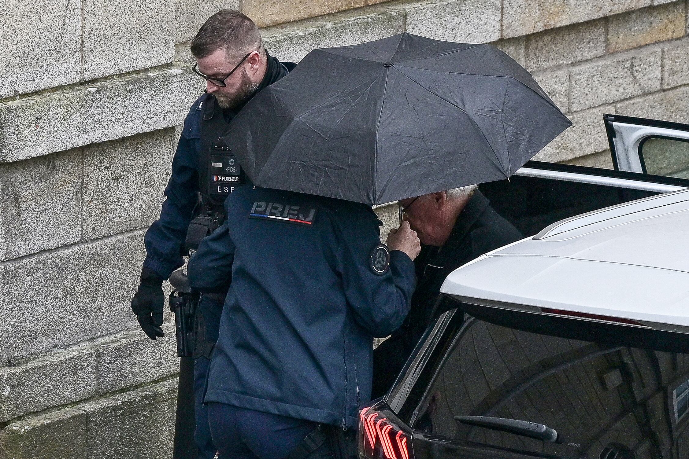 Retired surgeon Joel Le Scouarnec (R) arrives for his trial on charges of assaulting or raping 299 patients at the Criminal Court in Vannes, on February 25, 2025. Scouarnec, 74, faces a new four-month trial, charged with raping or sexually assaulting patients, most of them children and some of them unconscious at the time. He is already in jail after being found guilty in 2020 of abusing four children, including two of his nieces. (Photo by Damien MEYER / AFP)