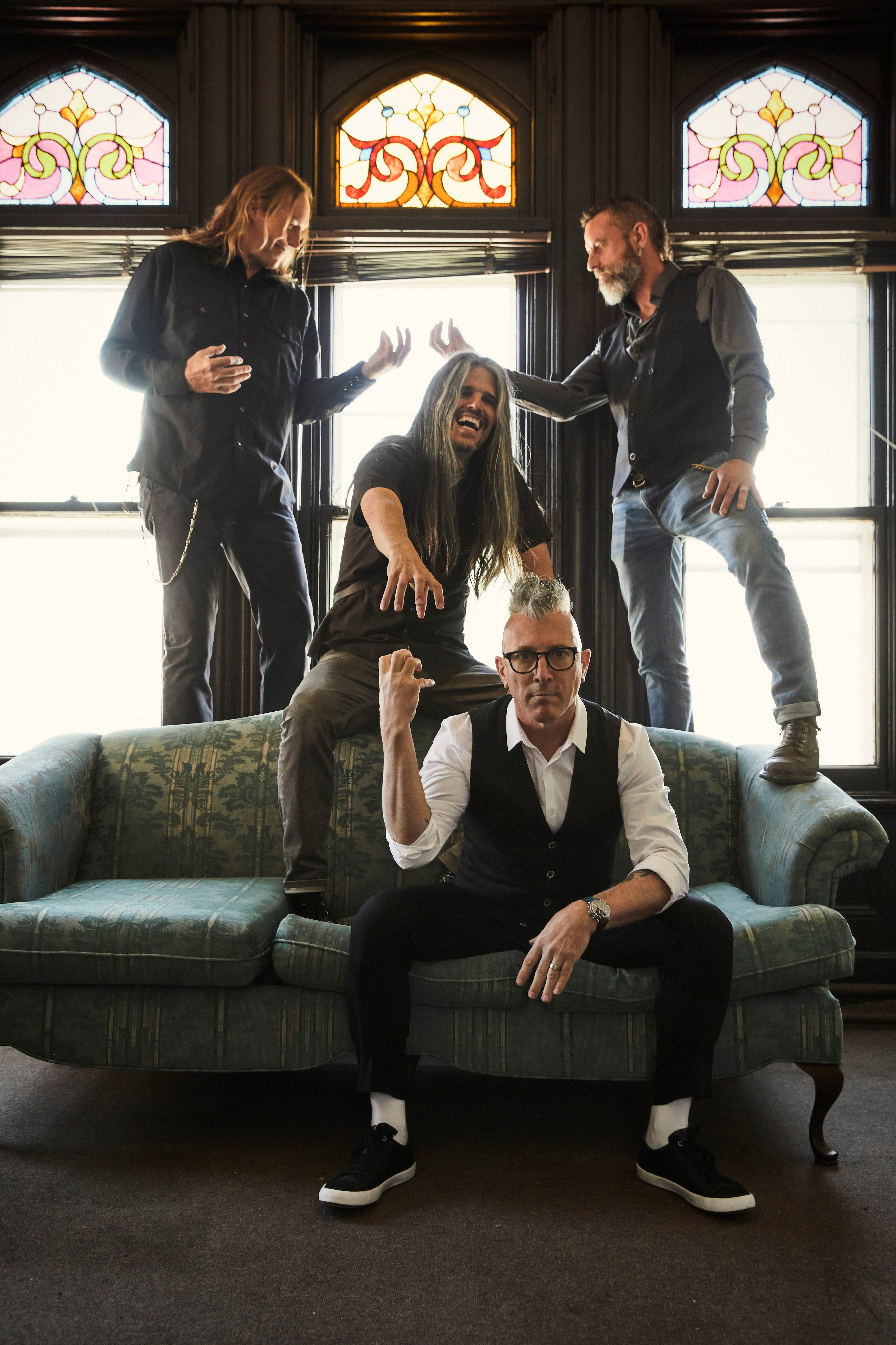 Imagen de la banda Tool. Los miembros del grupo posan en diferentes posiciones sobre un sillón.