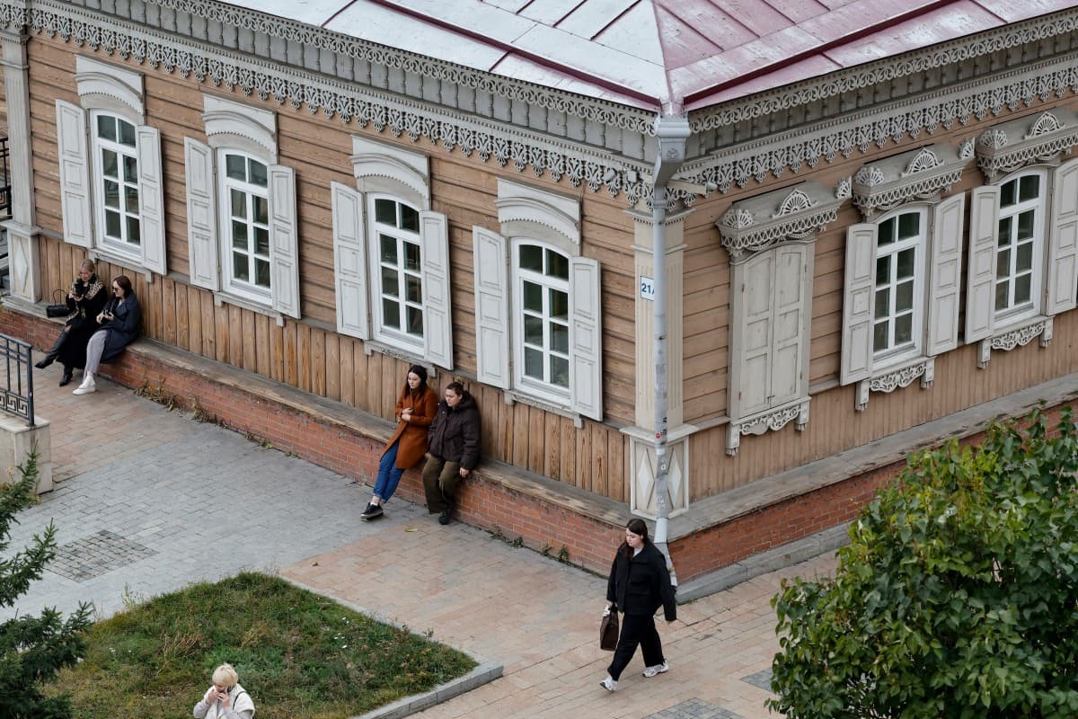 Unas mujeres caminan cerca de una tradicional casa de madera convertida en museo, en la ciudad siberiana de Irkutsk, el 8 de octubre de 2026.