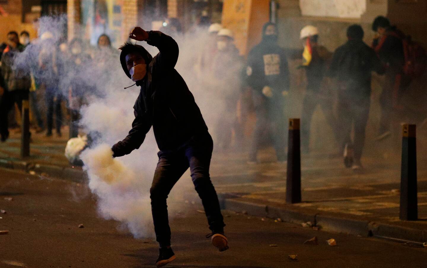 A demonstrator throws back a tear gas canister at the police during a protest against President Evo Morales' reelection, in La Paz, Bolivia, Wednesday, Nov. 6, 2019. Opponents challenged an official count that showed Morales winning with 47% of the vote and a margin of just over 10 percentage points over his nearest competitor, enough to avoid the need for a runoff against a united opposition. (AP Photo/Juan Karita)