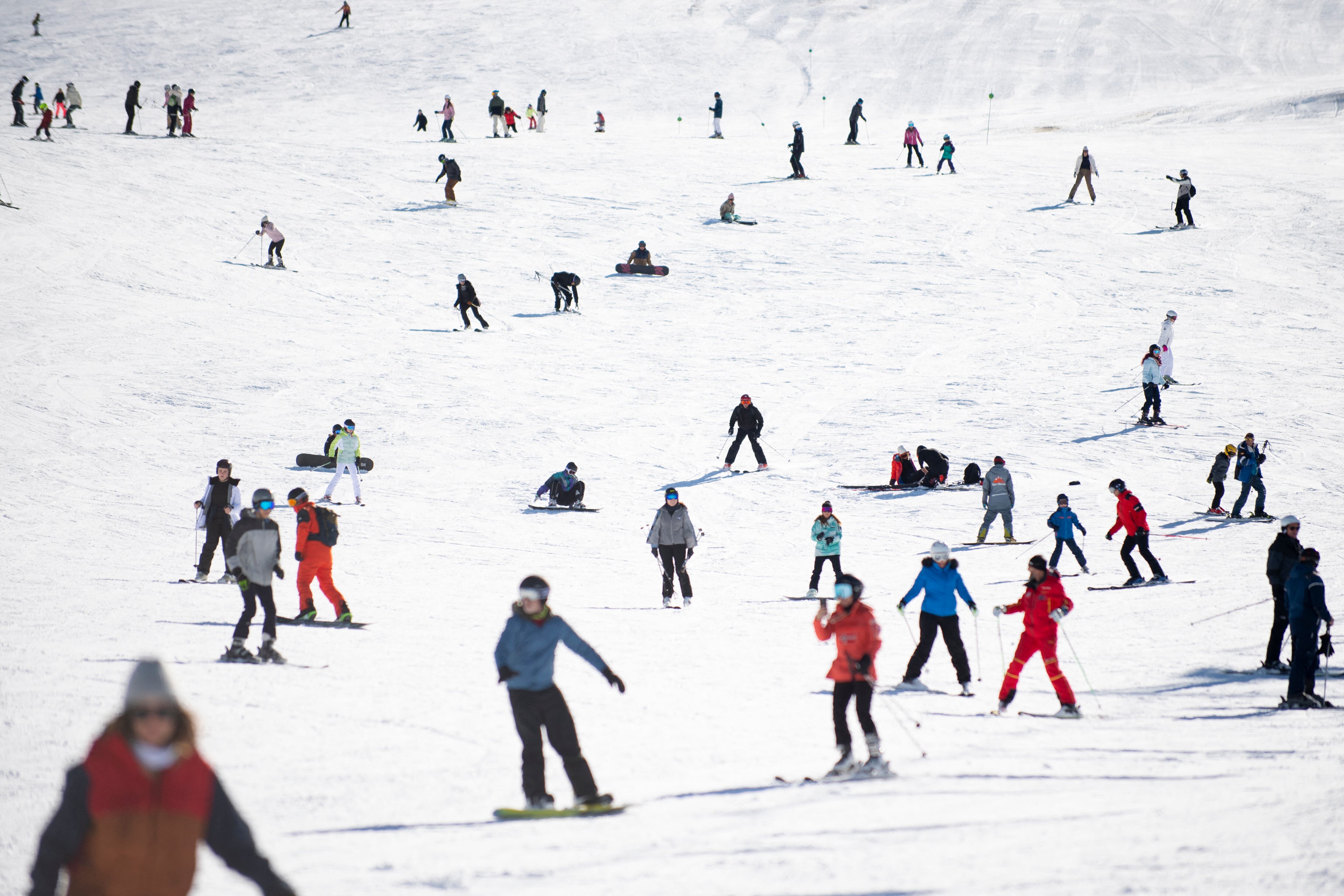 Personas practicando esquí y 'snowboarding' en una pista nevada en España, destacando el auge del turismo invernal como parte de la diversificación del sector turístico.
