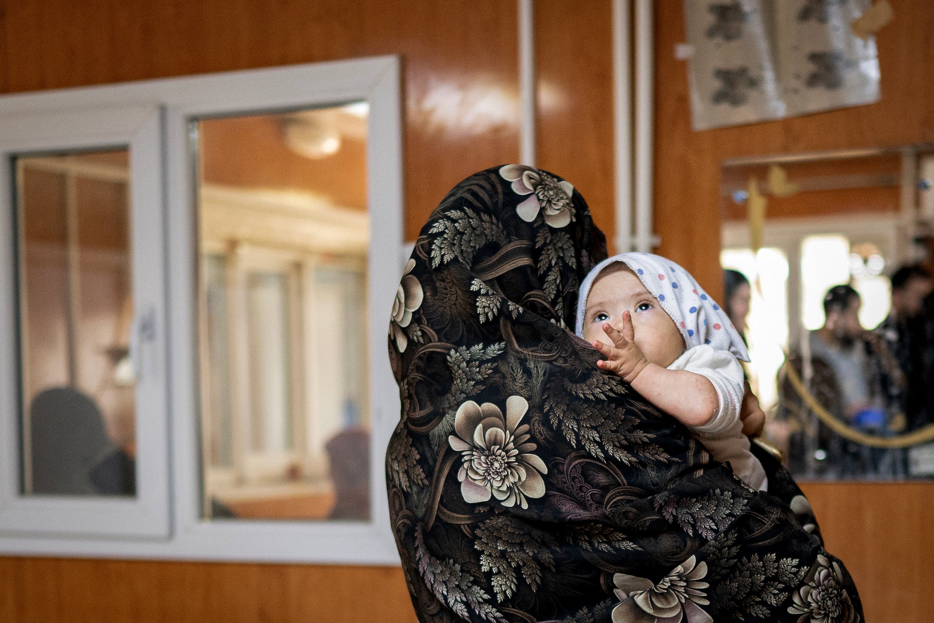 Esta fotografía, tomada el 8 de enero de 2026, muestra a Jamila, una mujer afgana, cargando a su hija de ocho meses tras una entrevista con AFP en el centro de Médicos Sin Fronteras (MSF) de un hospital en Herat.