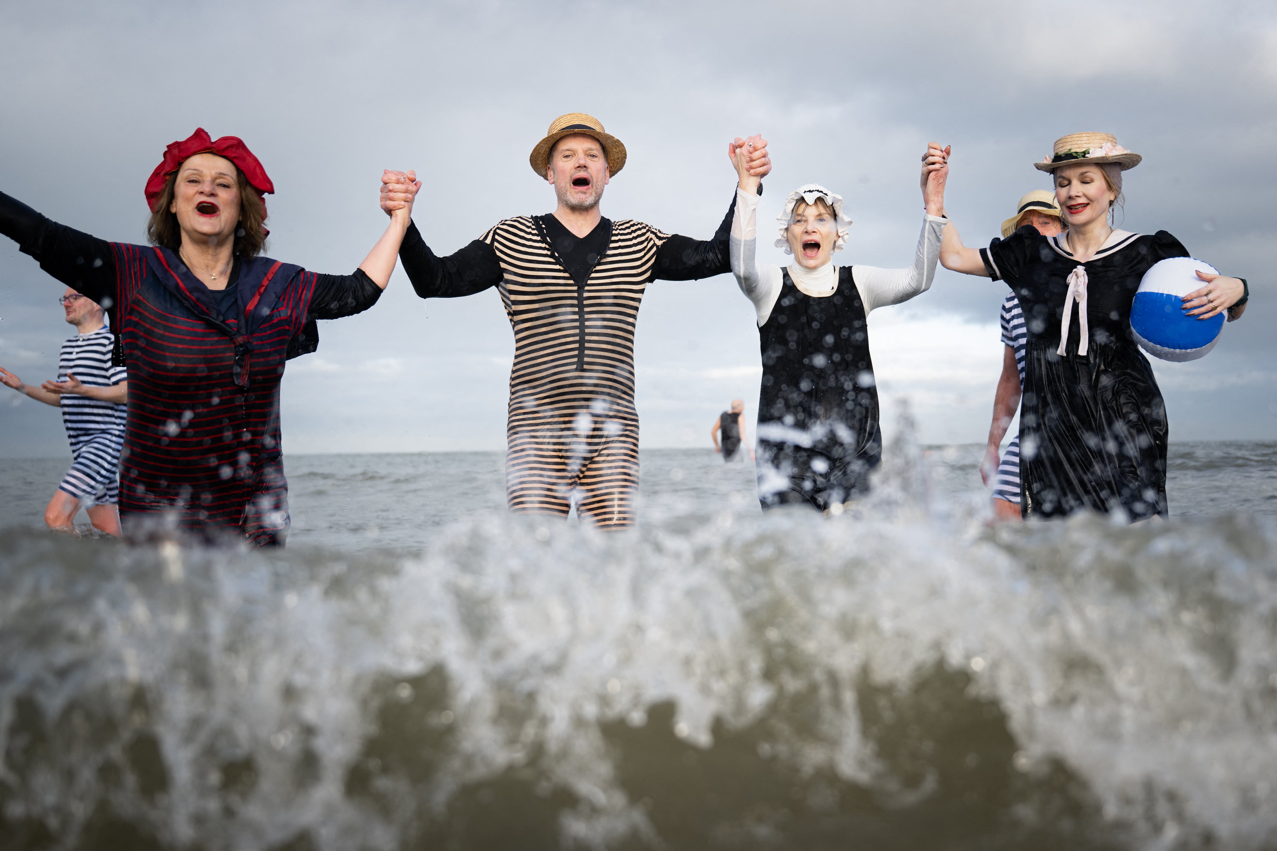 Participantes con trajes al estilo de 1900 se adentran en el mar durante el tradicional último baño del año en Cabourg, Francia, el 31 de diciembre de 2025.
