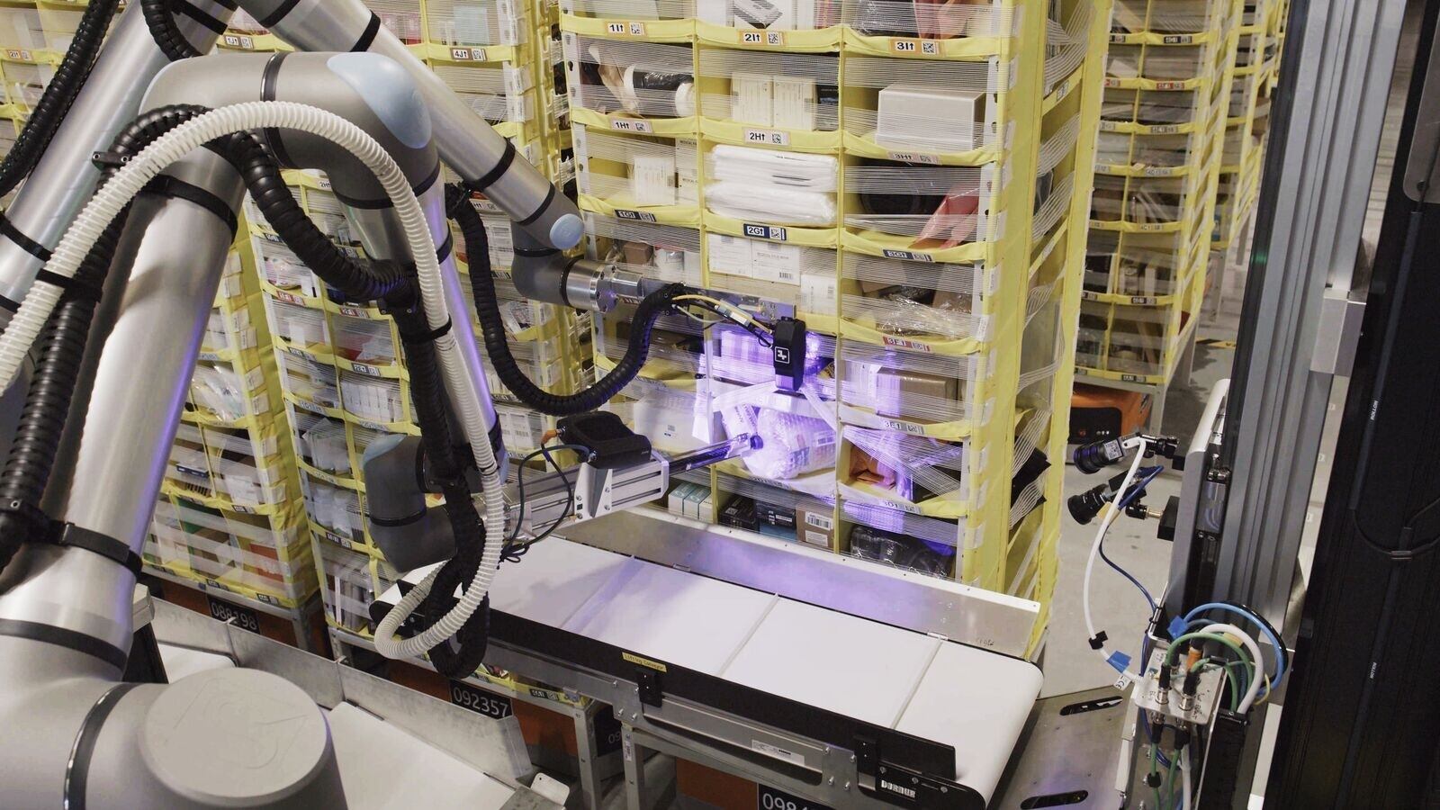 Robot Vulcan de Amazon manipulando productos en estanterías de un centro logístico, equipado con sensores de tacto y visión artificial para optimizar la eficiencia del procesamiento de pedidos.