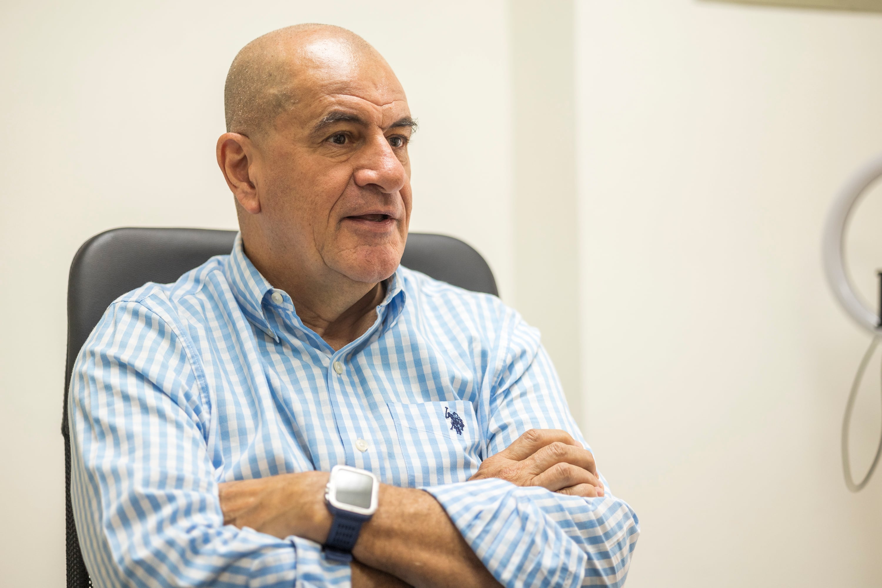 Danilo Montero, director de la Oficina del Consumidor Financiero, sentado en una oficina, con camisa a cuadros celeste y blanca.