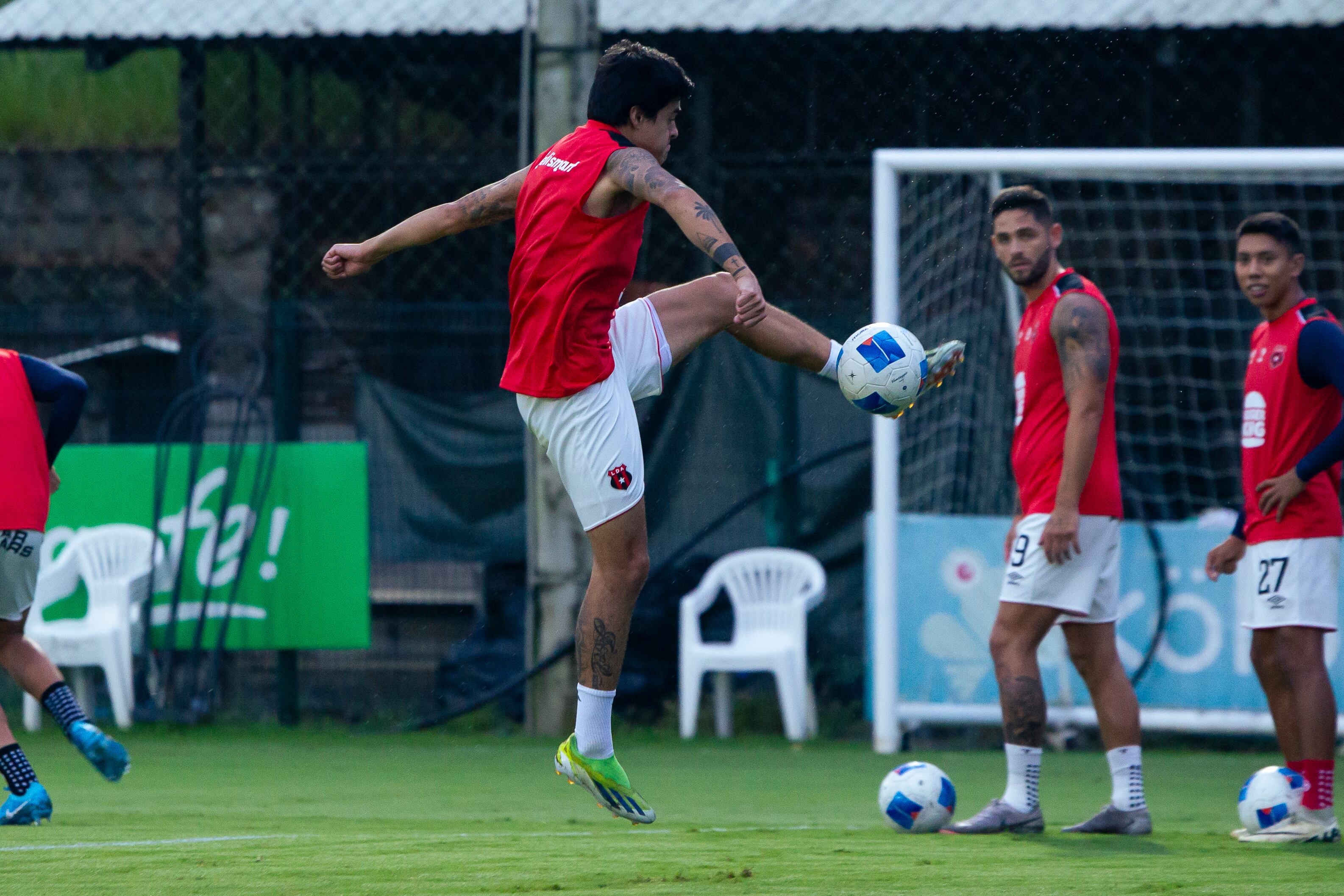 Diego Campos le pega al balón ante la mirada de Jonathan Moya y Carlos Martínez, en el entrenamiento previo al juego entre Liga Deportiva Alajuelense y Comunicaciones.