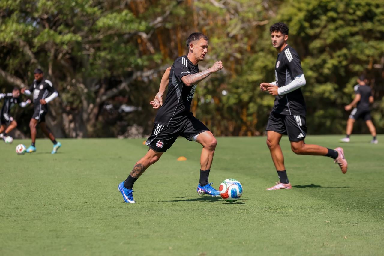 Christopher Núñez conduce un balón en el entrenamiento de la Selección Nacional, Fabod Samadian lo mira desde atrás.