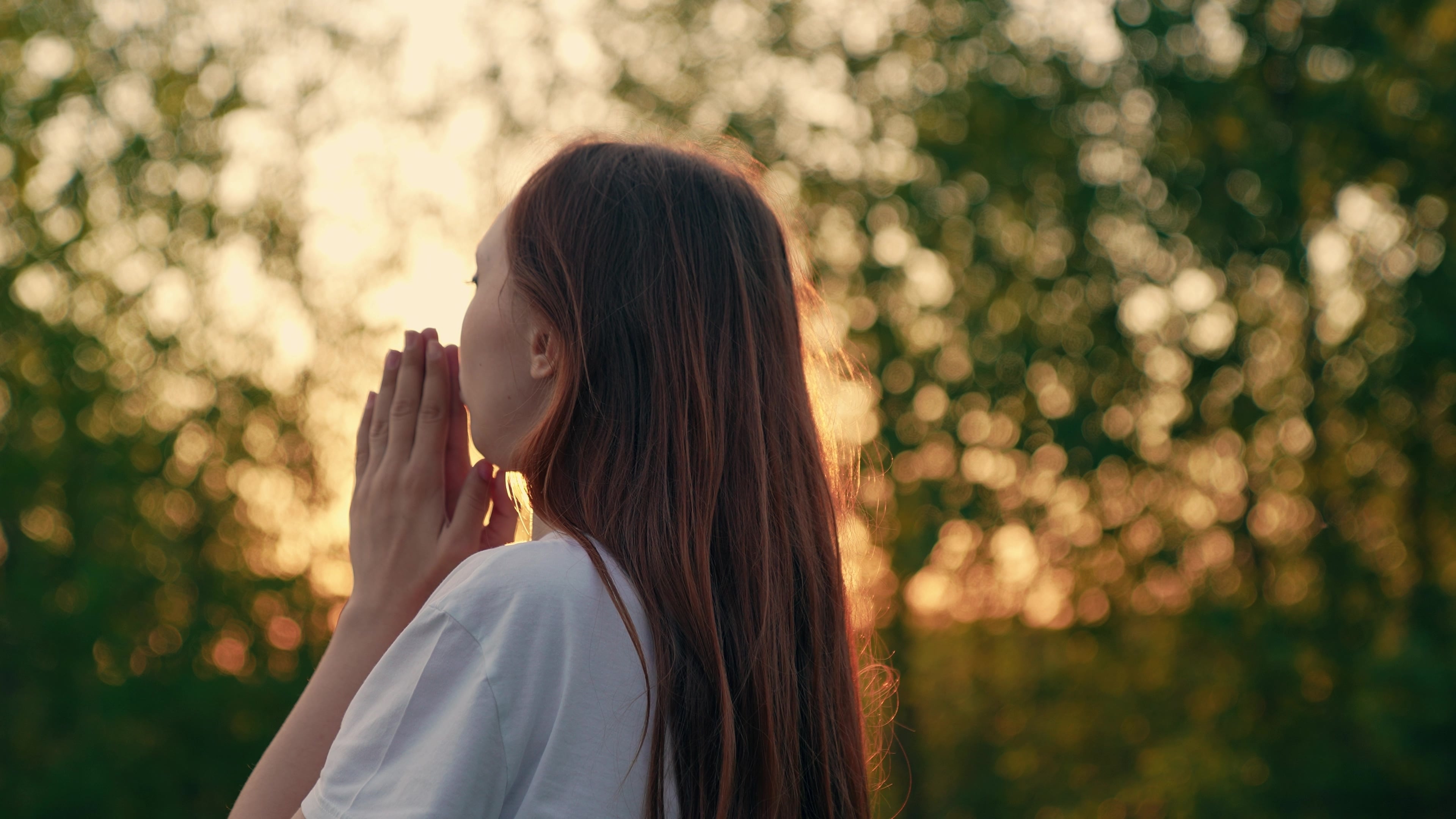 Mujer joven rezando al aire libre, en medio de la naturaleza, manos juntas, oración, meditación