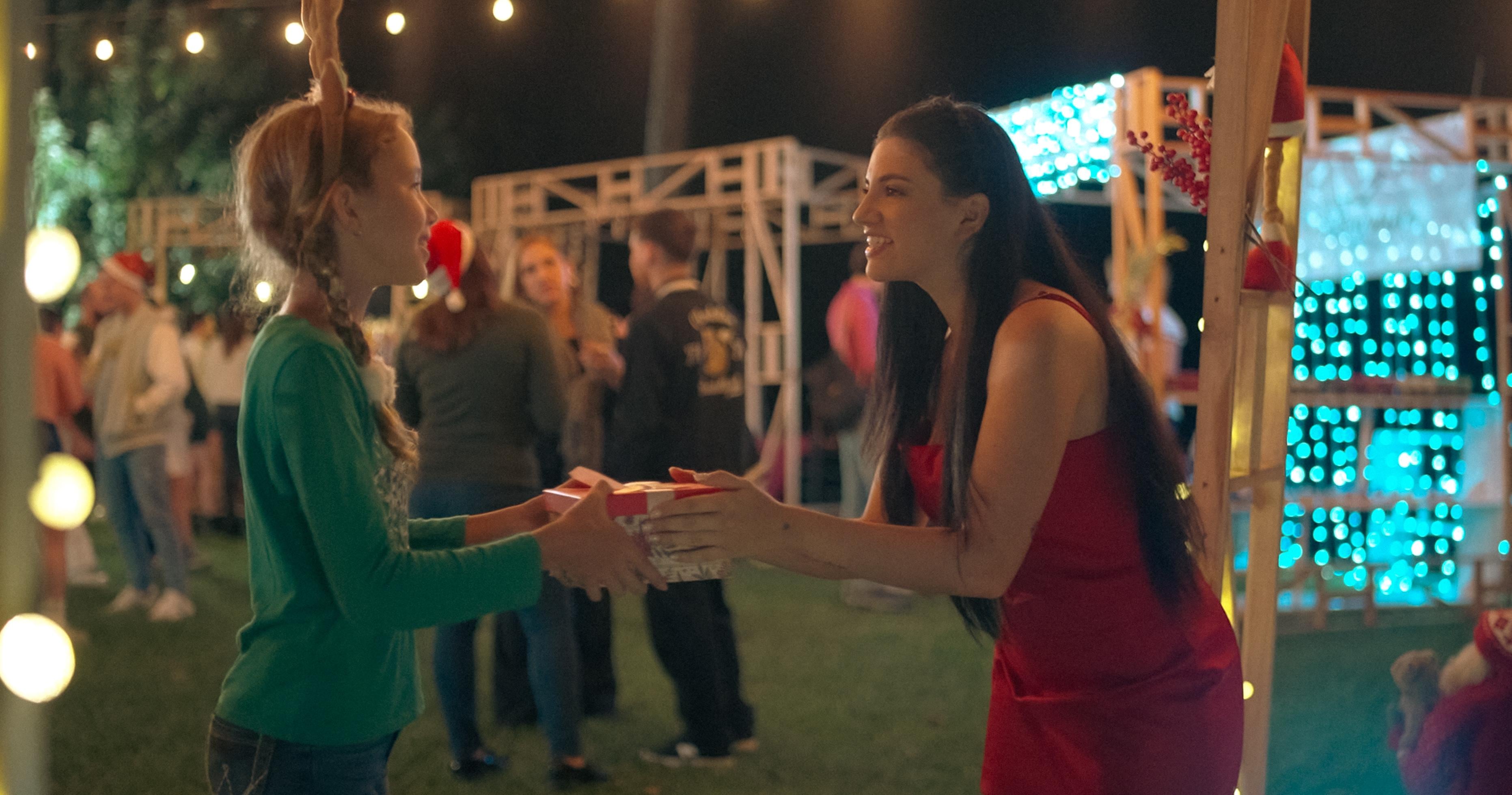 Escena de Una navidad sin nieve con Lucy entregando un regalo a una niña