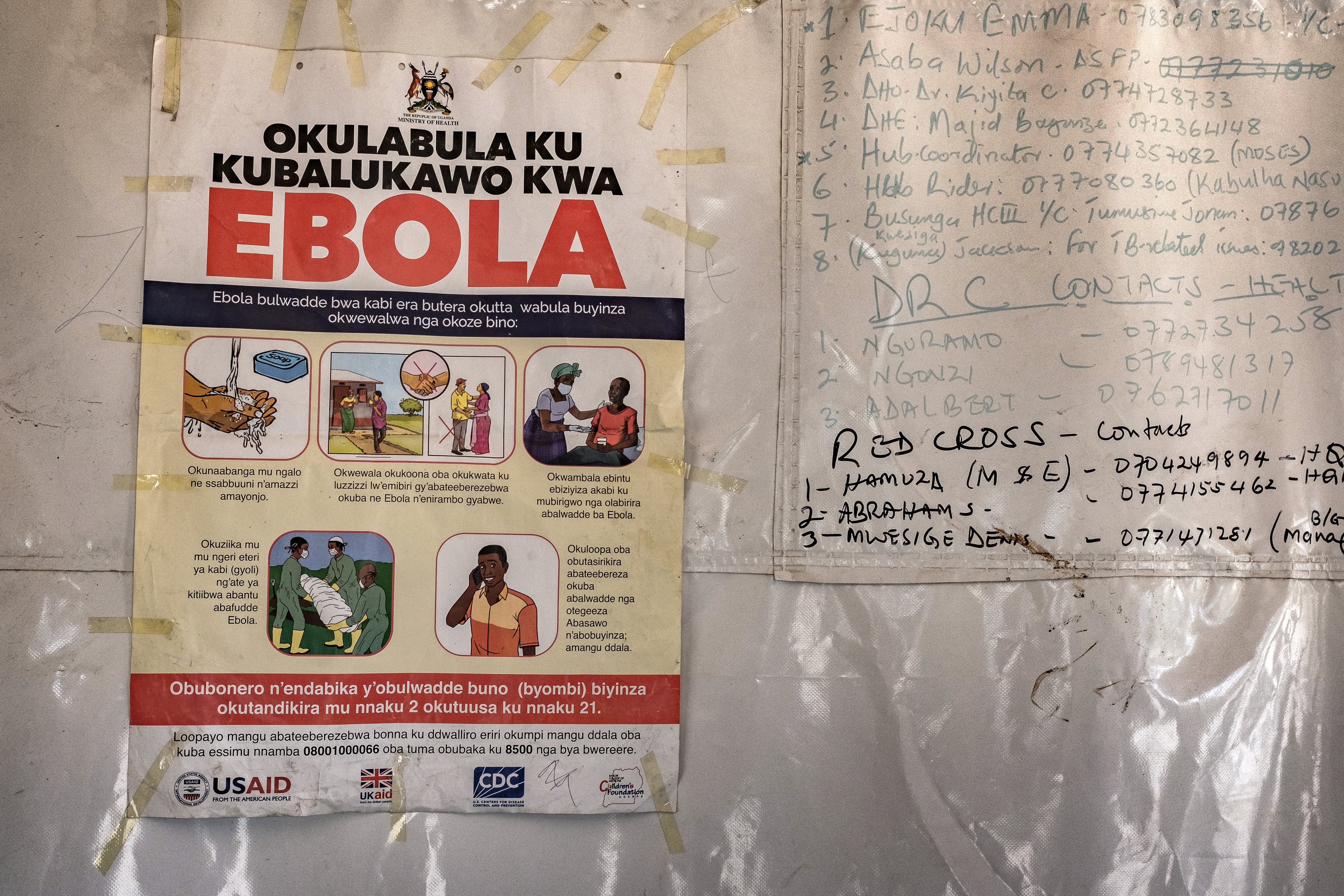 Un cartel con los números de contacto de emergencia para casos de ébola estaba fijado a una tienda de campaña en el paso fronterizo de Busunga