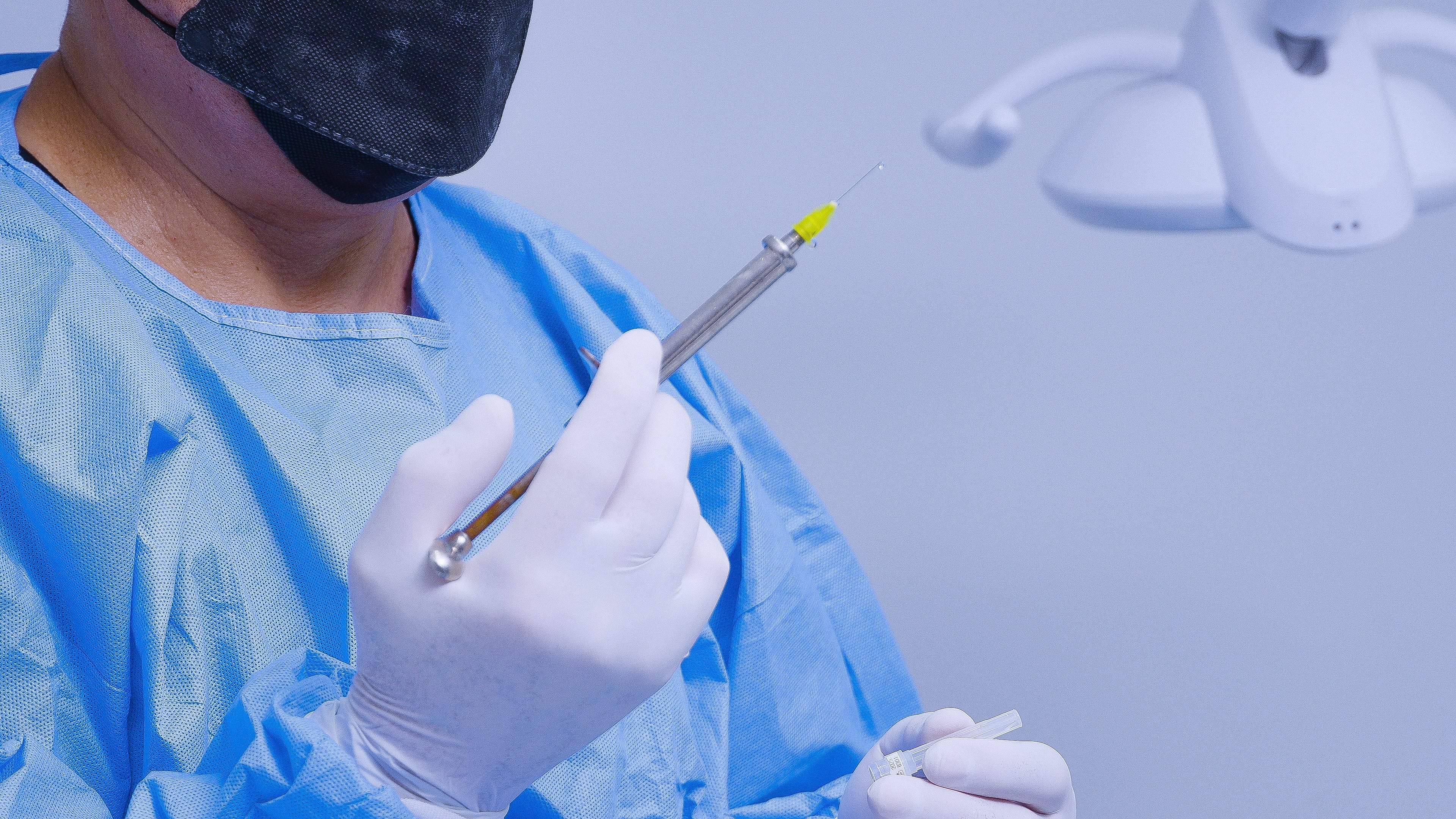 Médicos anestesiólogos, primer plano de médico uniformado con jeringa en la mano
