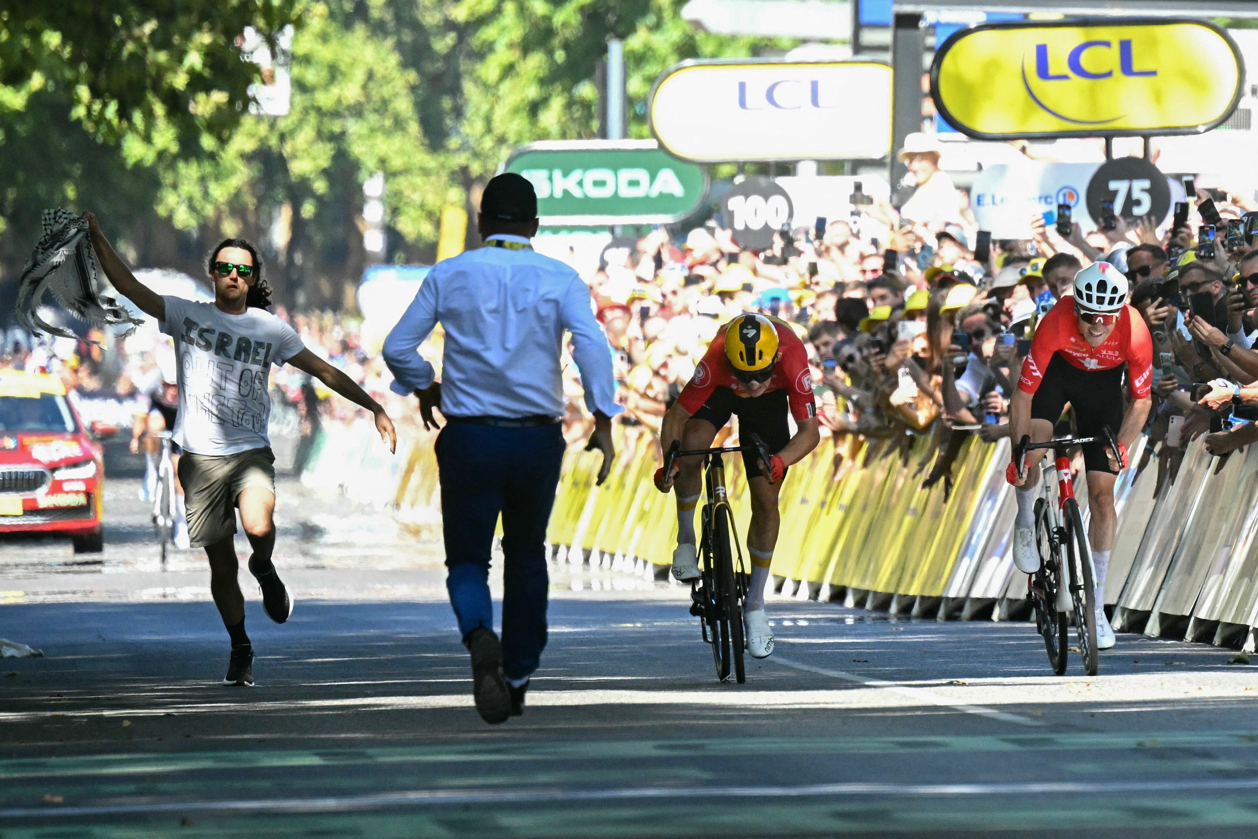 Un miembro del staff del Tour intercepta a un espontáneo que trató de entorpecer el sprint final de la etapa 11 entre Jonas Abrahamsen y Mauro Schmid.