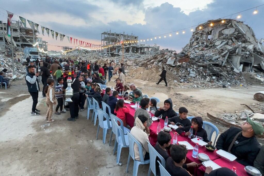 Palestinians gather for a communal iftar, or fast-breaking meal, on the first day of the Muslim holy month of Ramadan, amid building rubble in Rafah in the southern Gaza Strip on March 1, 2025. (Photo by AFP)