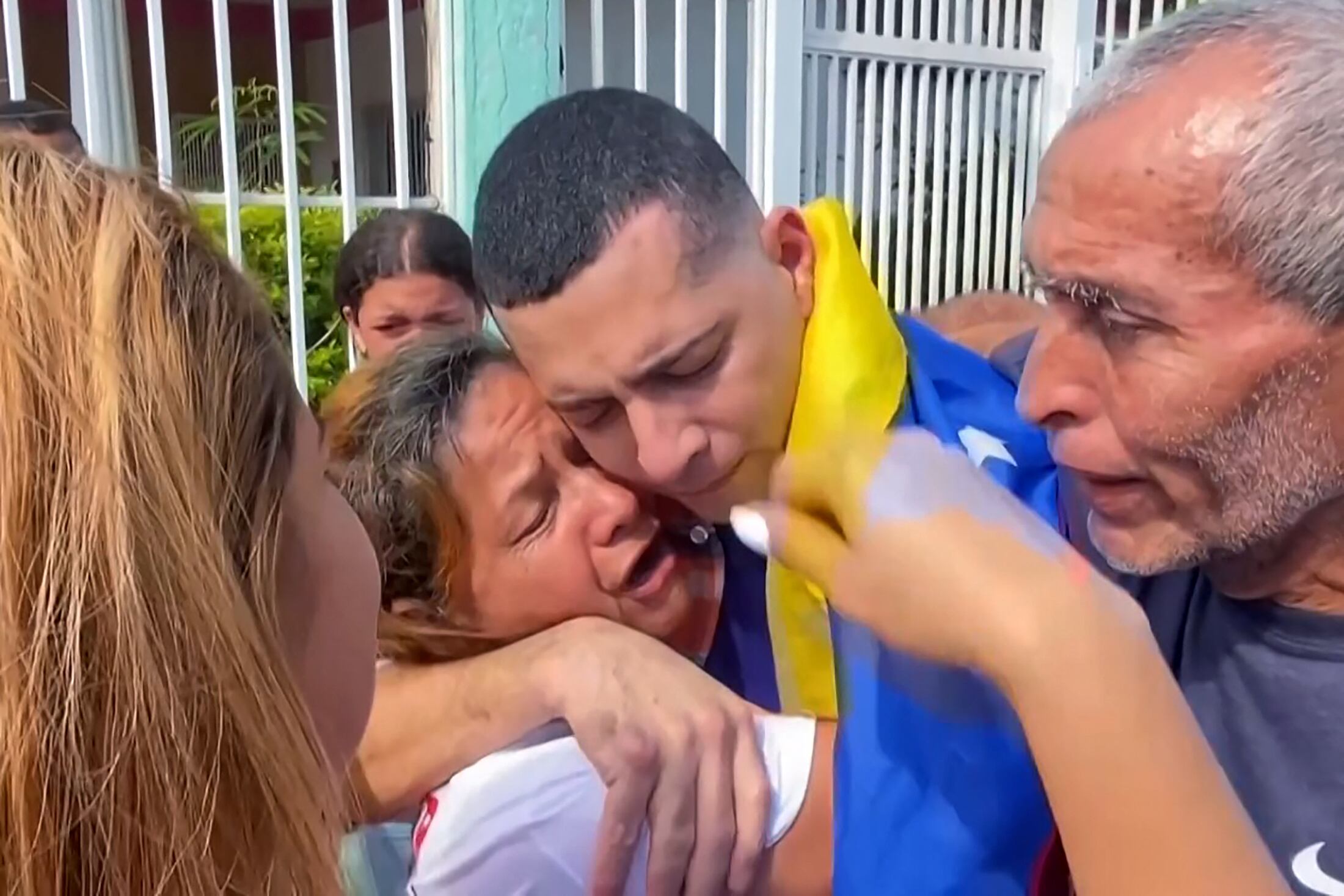 Esta imagen tomada de un video de AFPTV muestra a Maikel Olivera (centro), un migrante venezolano liberado de una notoria prisión salvadoreña, abrazando a su madre Olivia Rojas durante el reencuentro con su familia en Barquisimeto, estado Lara, Venezuela, el 22 de julio de 2025. Cientos de venezolanos detenidos en la ofensiva migratoria de Donald Trump fueron liberados abruptamente de una cárcel salvadoreña de máxima seguridad y repatriados como parte de un intercambio de prisioneros el 18 de julio, poniendo fin a una prolongada y mediática odisea. Los 252 hombres fueron acusados —sin pruebas— de ser miembros de pandillas y enviados en marzo pasado a la temida prisión “antiterrorista” CECOT. (Foto: Ramón Véliz / AFPTV / AFP)