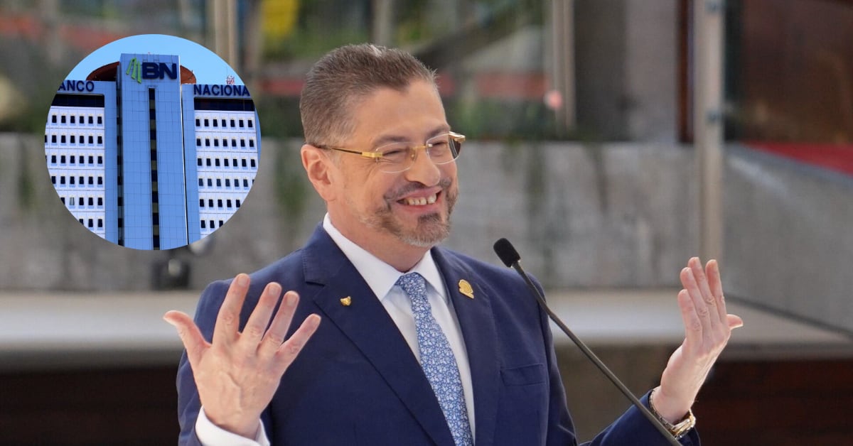 UN hombre de traje y lentes, sonriente y los brazos abiertos en una fotocomposición que incluye un edificio de varios pisos.