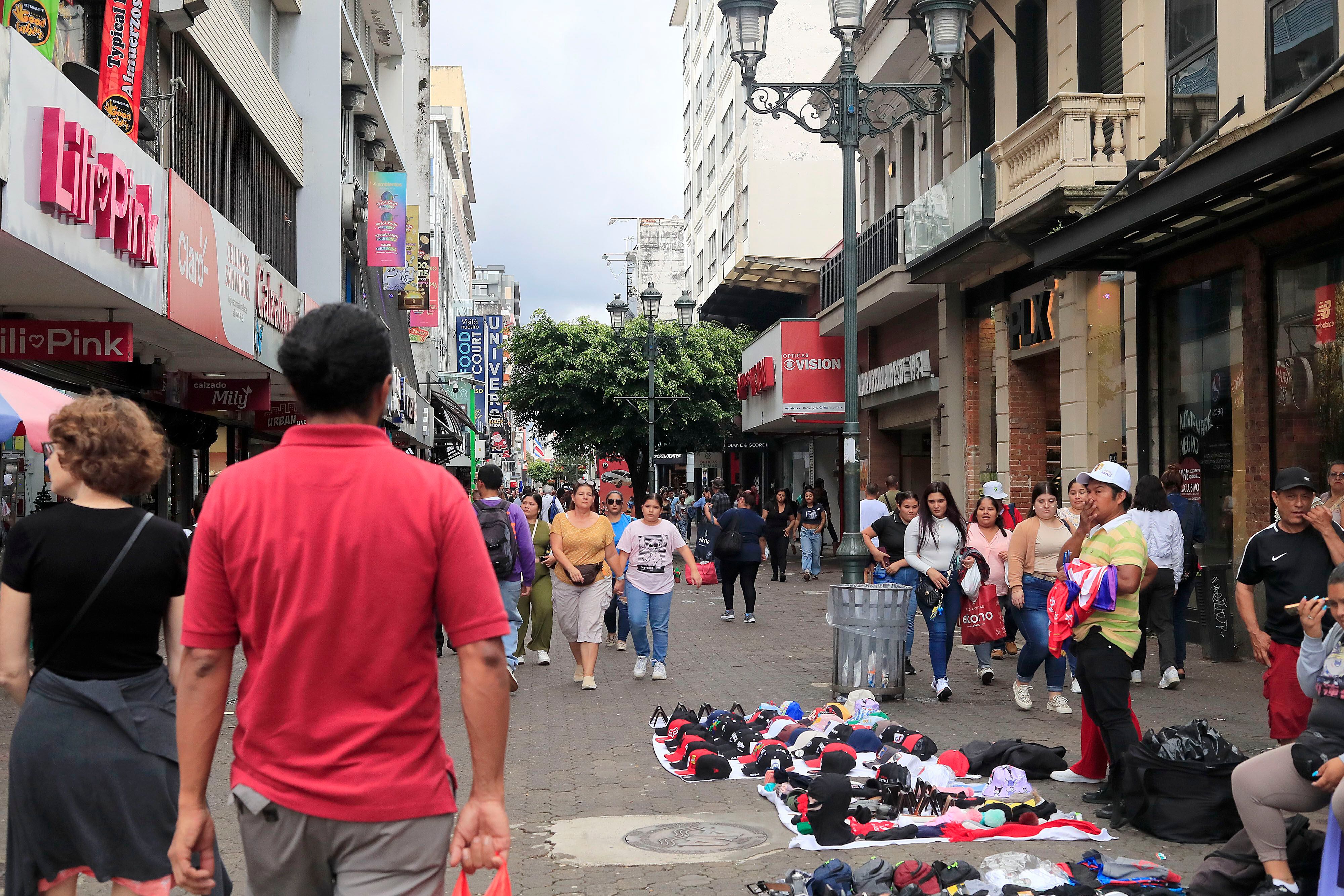 Vista de la Avenida Central en San José, Costa Rica, con peatones transitando entre tiendas y vendedores ambulantes. La percepción económica de los costarricenses para 2025 es mayoritariamente negativa, según un estudio.