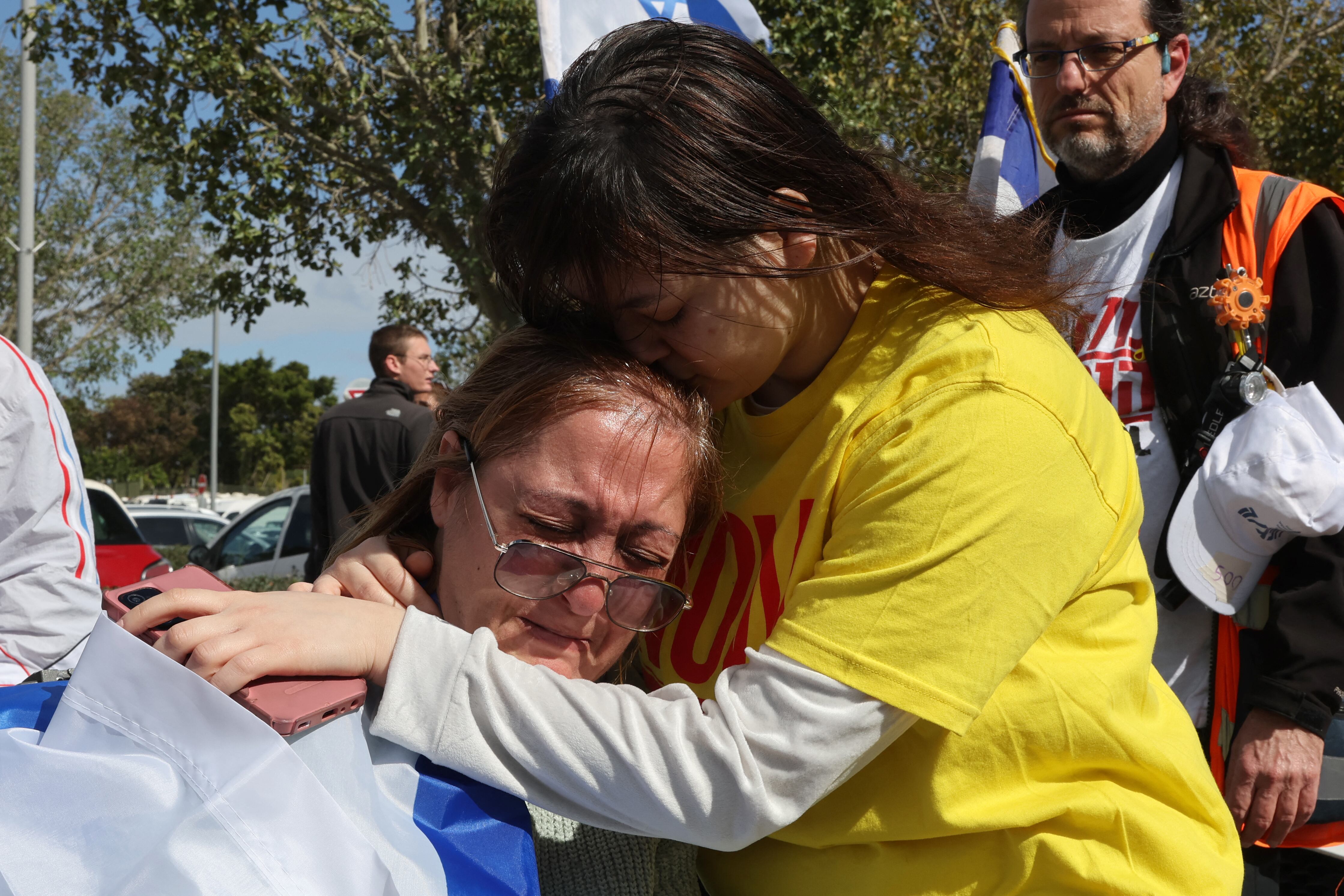 Israeli women cry upon the arrival of the convoy of vehicles transporting the bodies of the four Israeli hostages handed over by Hamas, at the National Center of Forensic Medicine in Tel Aviv on February 20, 2025. Hamas handed over the bodies of four hostages on February 20,