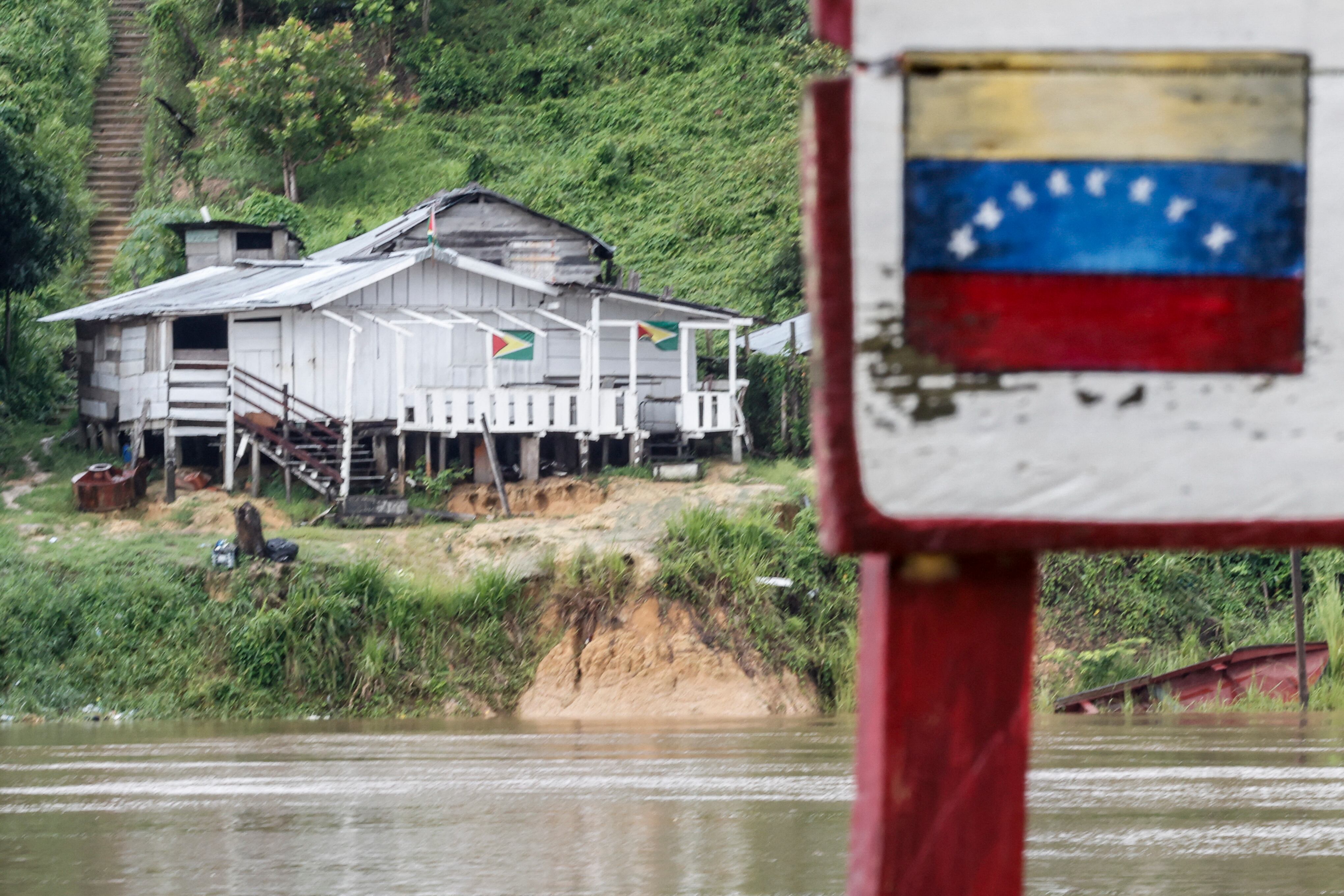 Vista de casas en la región del Esequibo o Guayana Esequiba con banderas de Guyana, a orillas del río Cuyuni, vistas desde el pueblo de San Martín de Turumbang, en el estado Bolívar, Venezuela, el 26 de mayo de 2025.