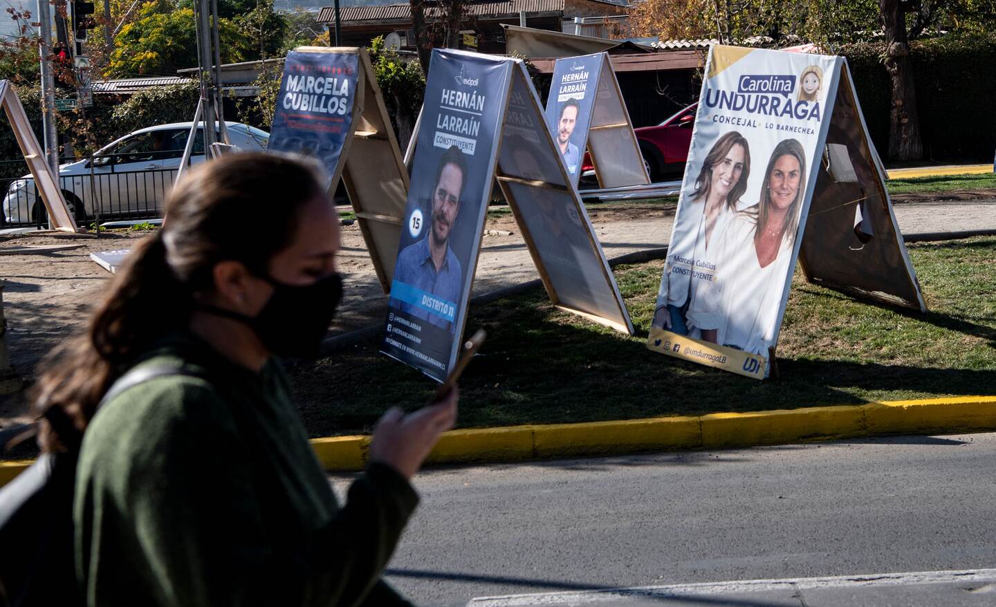 A woman walks past electoral propaganda in the commune of El Bosque in Santiago, on May 7, 2021. - On Saturday 15 and Sunday 16 of May elections will be held in Chile to elect mayors, councillors and a commission to rewrite the country's constitution. (Photo by MARTIN BERNETTI / AFP)