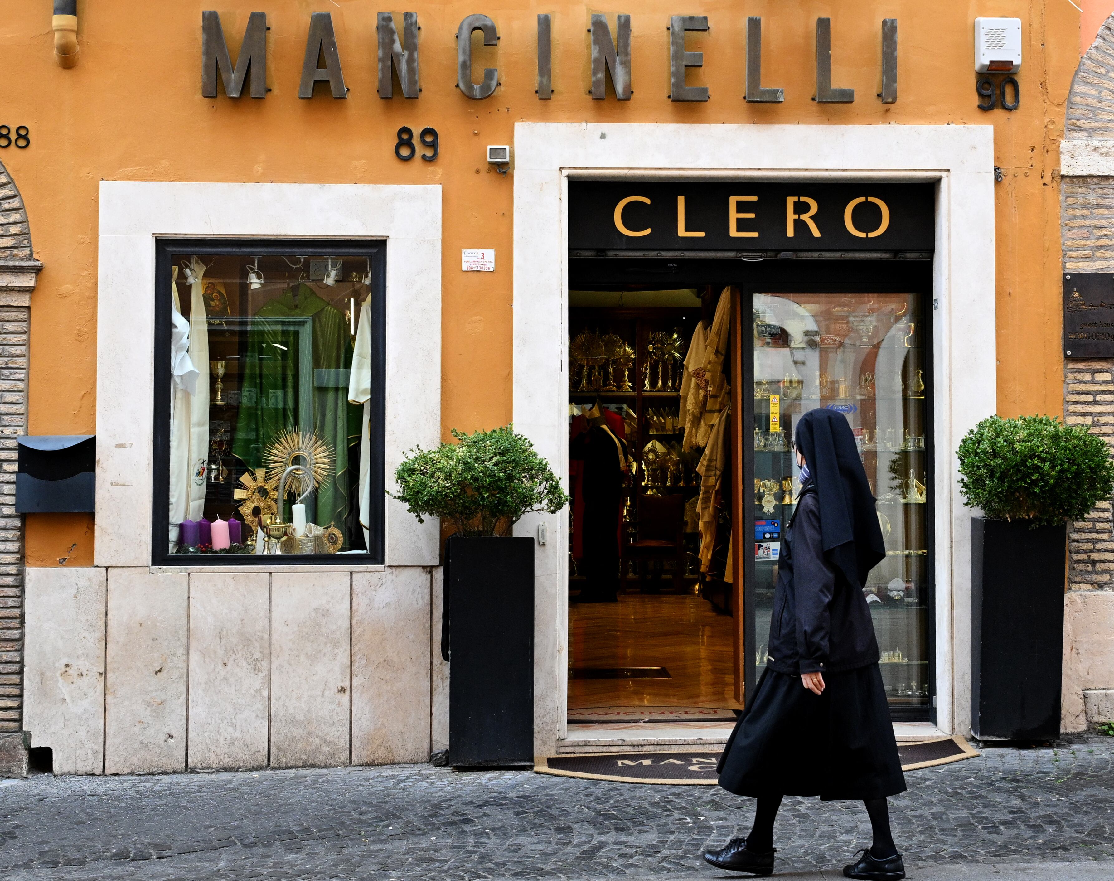 Una monja pasa frente a la tienda del sastre eclesiástico italiano Raniero Mancinelli, de 86 años, en Borgo Pio, un barrio cercano al Vaticano, el 19 de noviembre de 2024 en Roma. Los días se han convertido en una carrera contra el tiempo para Mancinelli, ya que un tercio de los 21 prelados que serán nombrados cardenales por el papa Francisco el 7 de diciembre de 2024 han hecho pedidos con él. (Foto de Tiziana FABI / AFP)