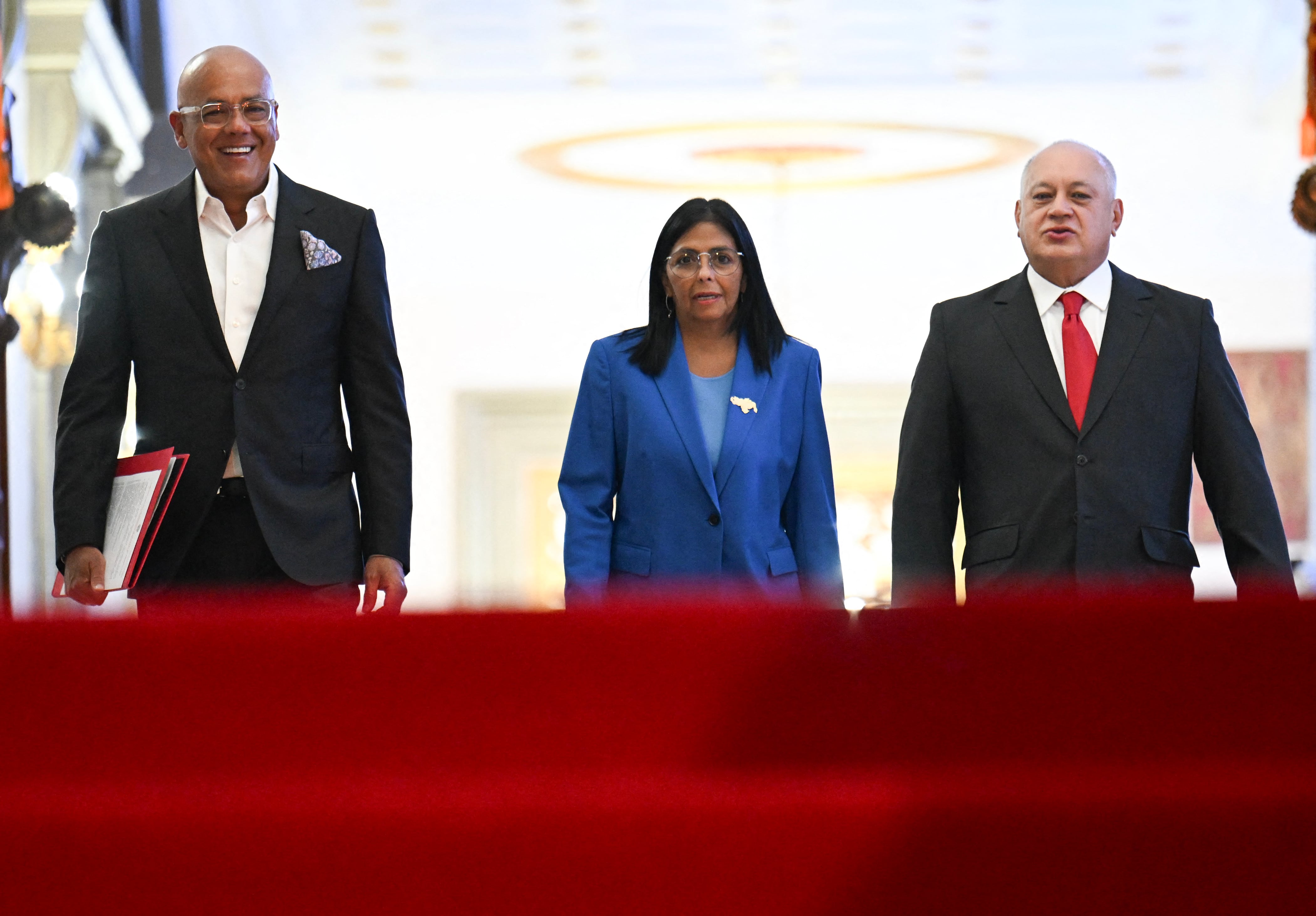 Venezuela�s interim president Delcy Rodriguez, with the president of the National Assembly, Jorge Rodriguez (L), and the Minister of Interior, Justice and Peace, Diosdado Cabello (R), walks before signing the amnesty law approved by the National Assembly at the Miraflores Palace in Caracas on February 19, 2026. Venezuela's Parliament unanimously approved on February 19 a historic amnesty law that is expected to lead to the release of hundreds of political prisoners after 27 years of Chavismo. (Photo by Juan BARRETO / AFP)