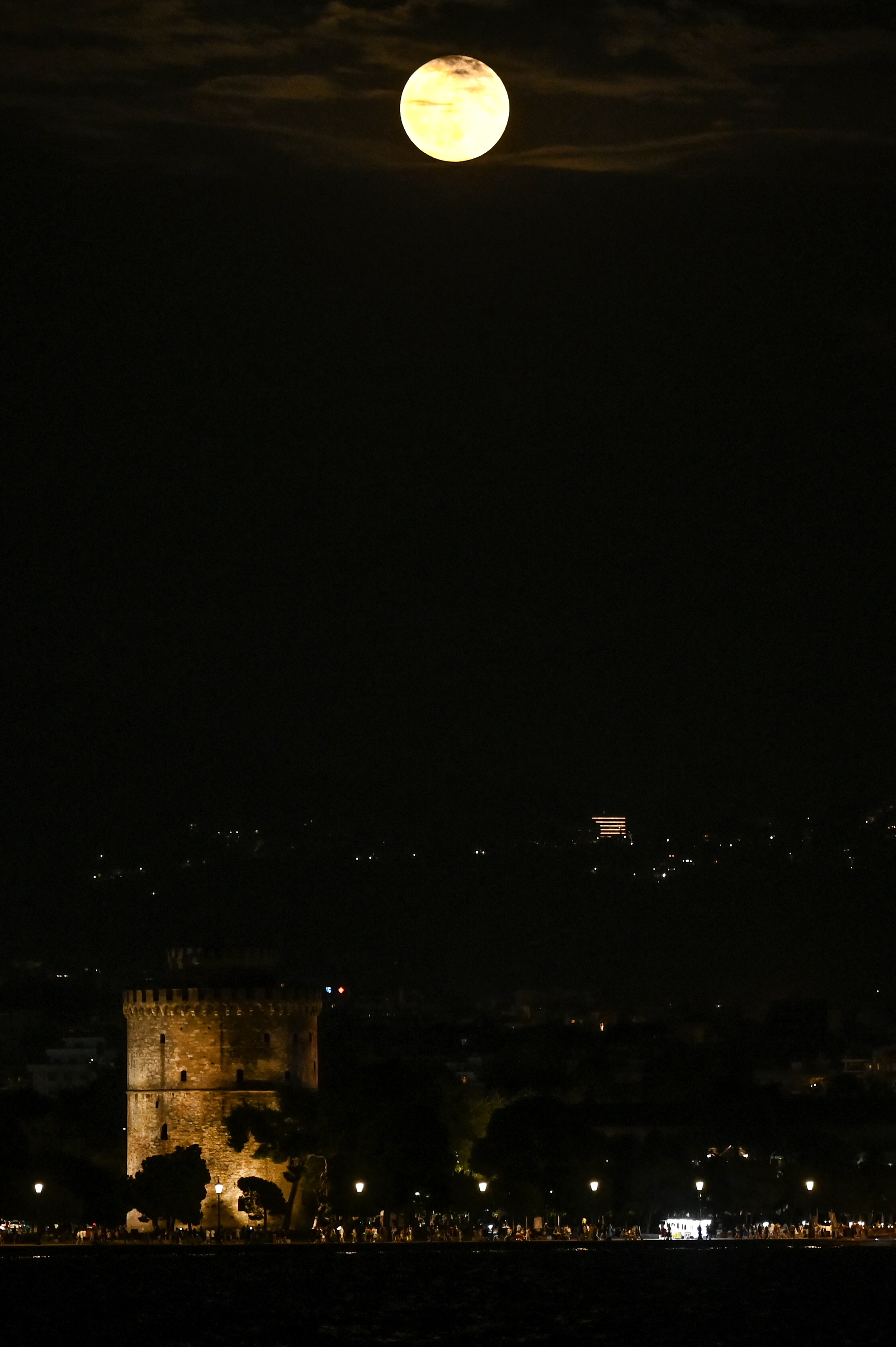 Super blue moon rises over the White Tower in Thessaloniki on August 19, 2024. (Photo by Sakis MITROLIDIS / AFP)