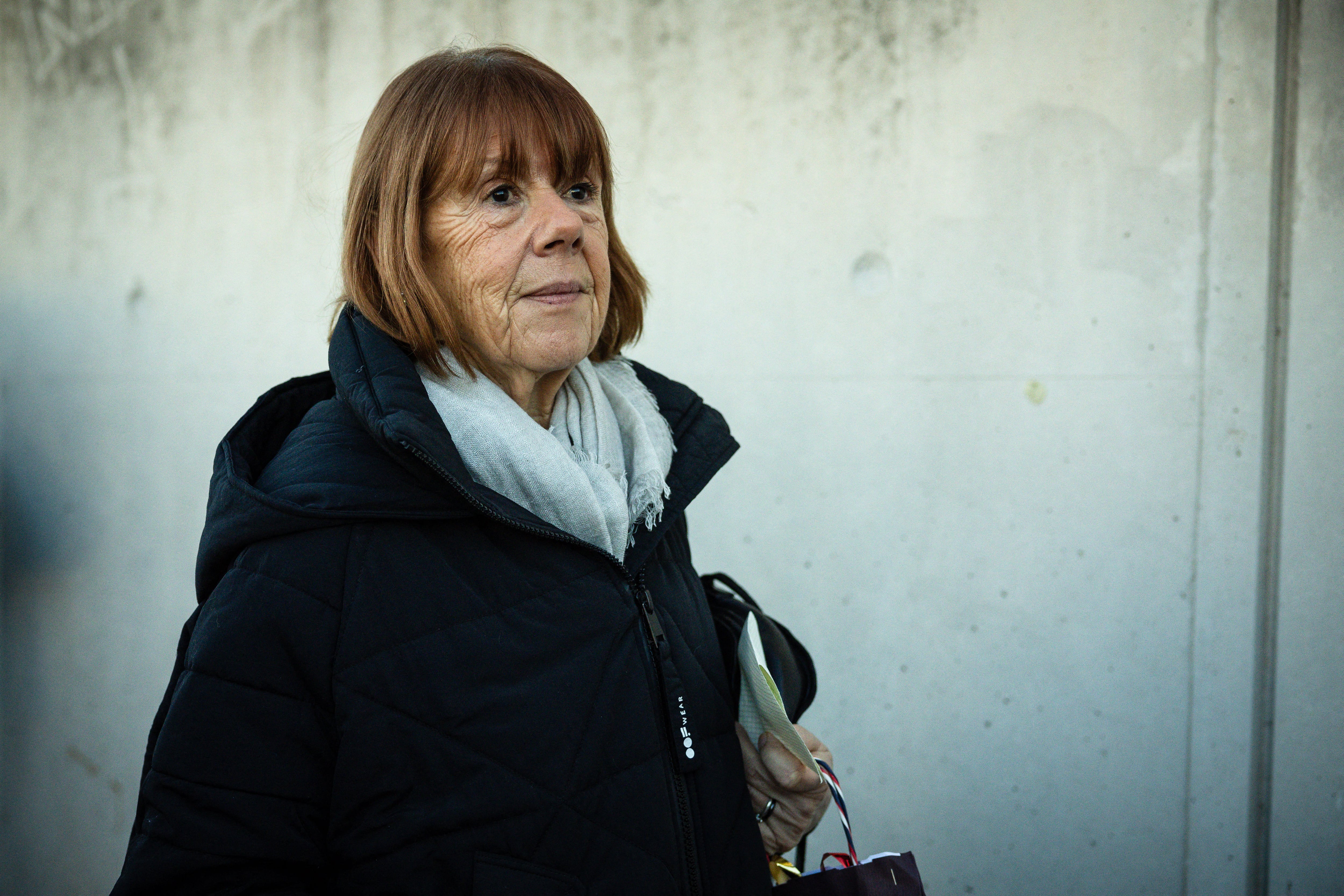 Gisele Pelicot, una mujer con cabello castaño, vestida con abrigo negro y bufanda gris, sale del juzgado de Avignon tras escuchar los alegatos finales en el juicio de su expareja, acusada de drogarla y permitir violaciones durante diez años.
