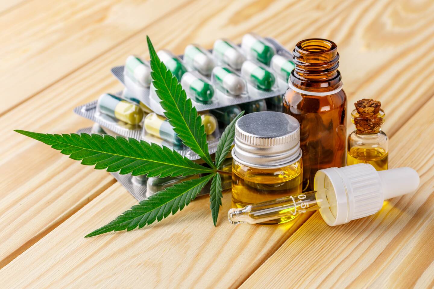 Una hoja de la planta "Cannabis sativa", y presentaciones de tabletas, cápsulas y aceites.