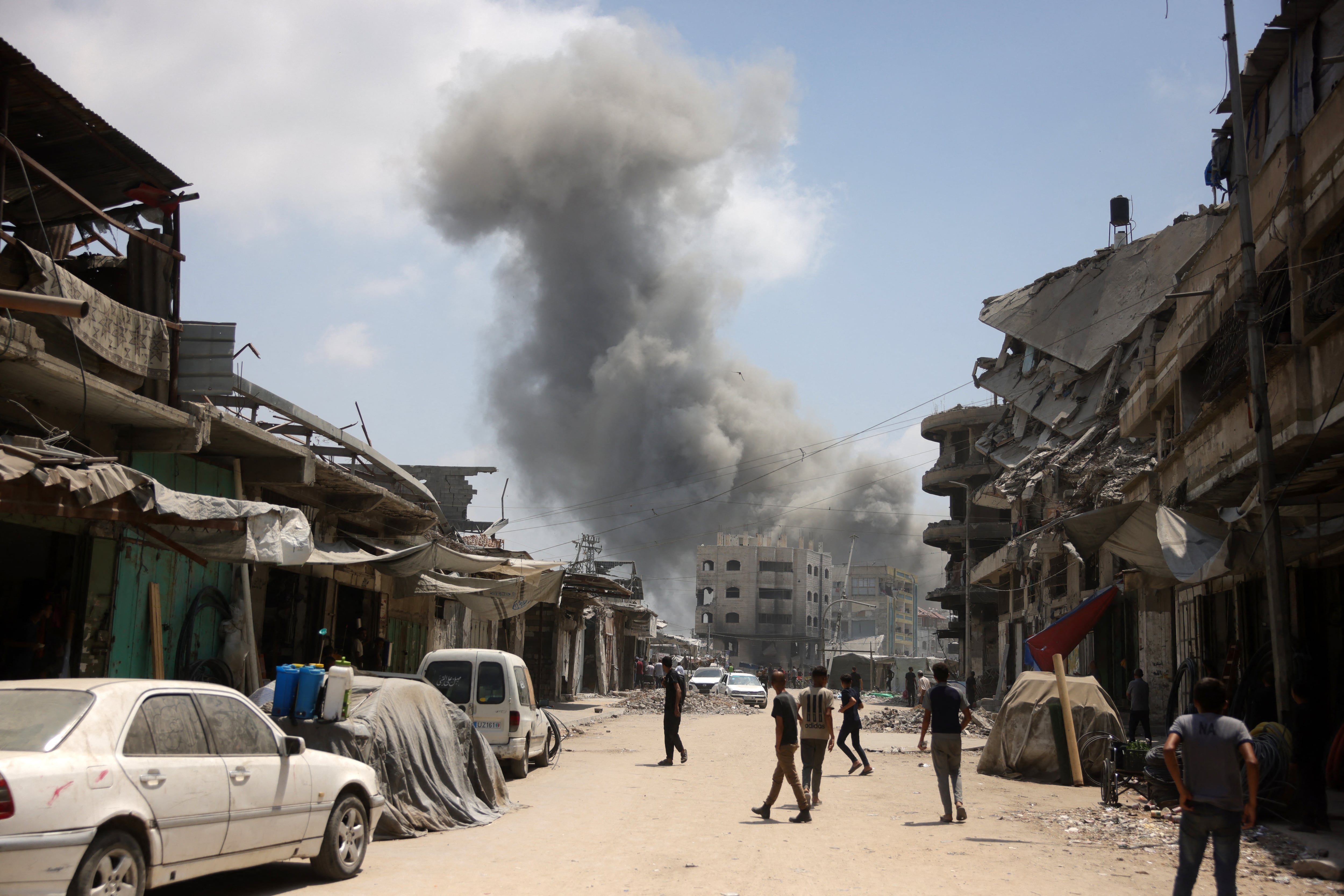Palestinos frente a una columna de humo durante un ataque israelí contra el barrio de Al-Zeitoun, al sur de la Ciudad de Gaza, este 8 de agosto. Fotografía: