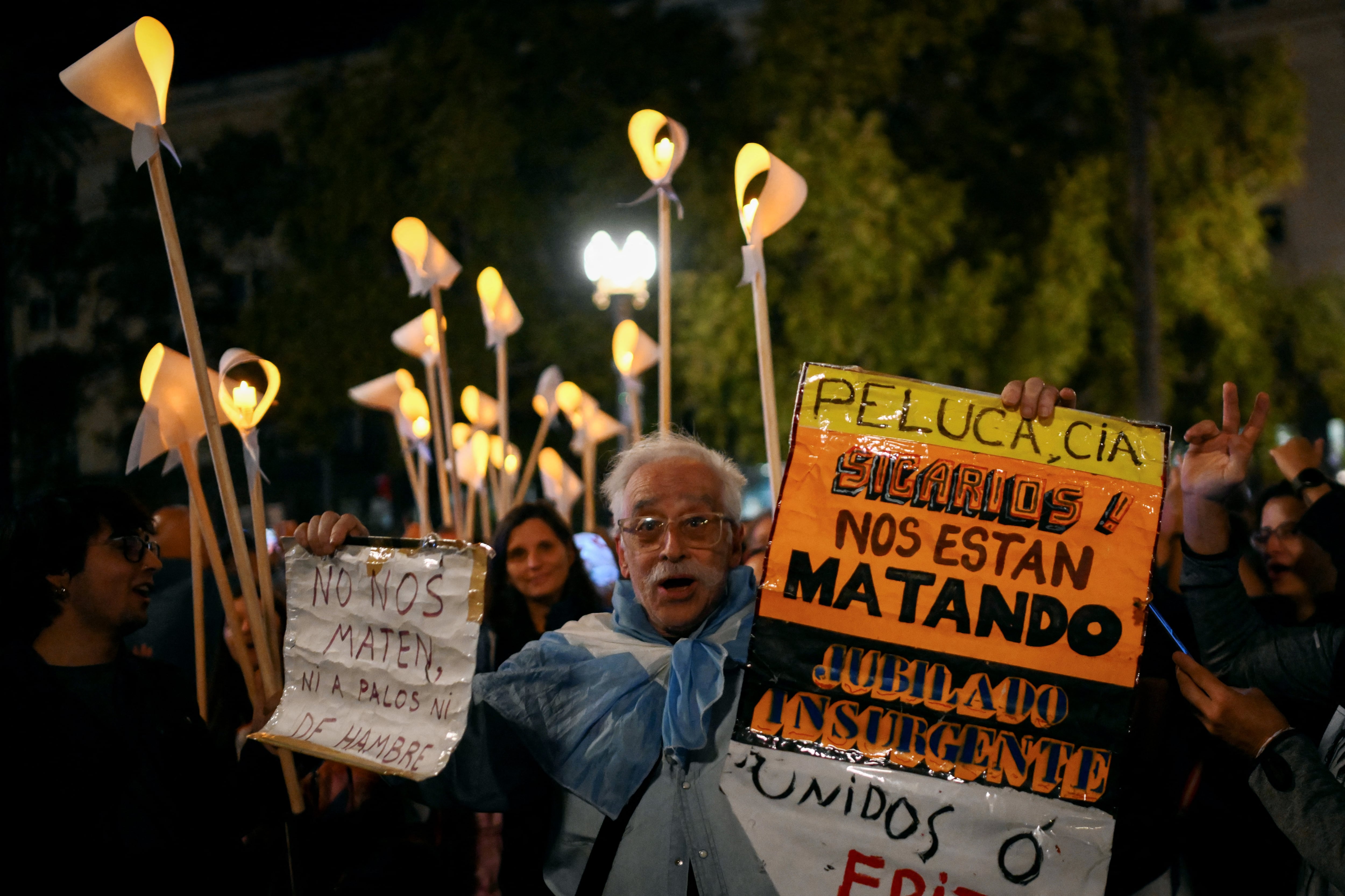 Un hombre sostiene un cartel mientras personas se reúnen en la Plaza de Mayo, en Buenos Aires, el 23 de marzo de 2026, durante una vigilia previa al 50 aniversario del golpe de Estado que dio inicio a la dictadura militar (1976-1983).