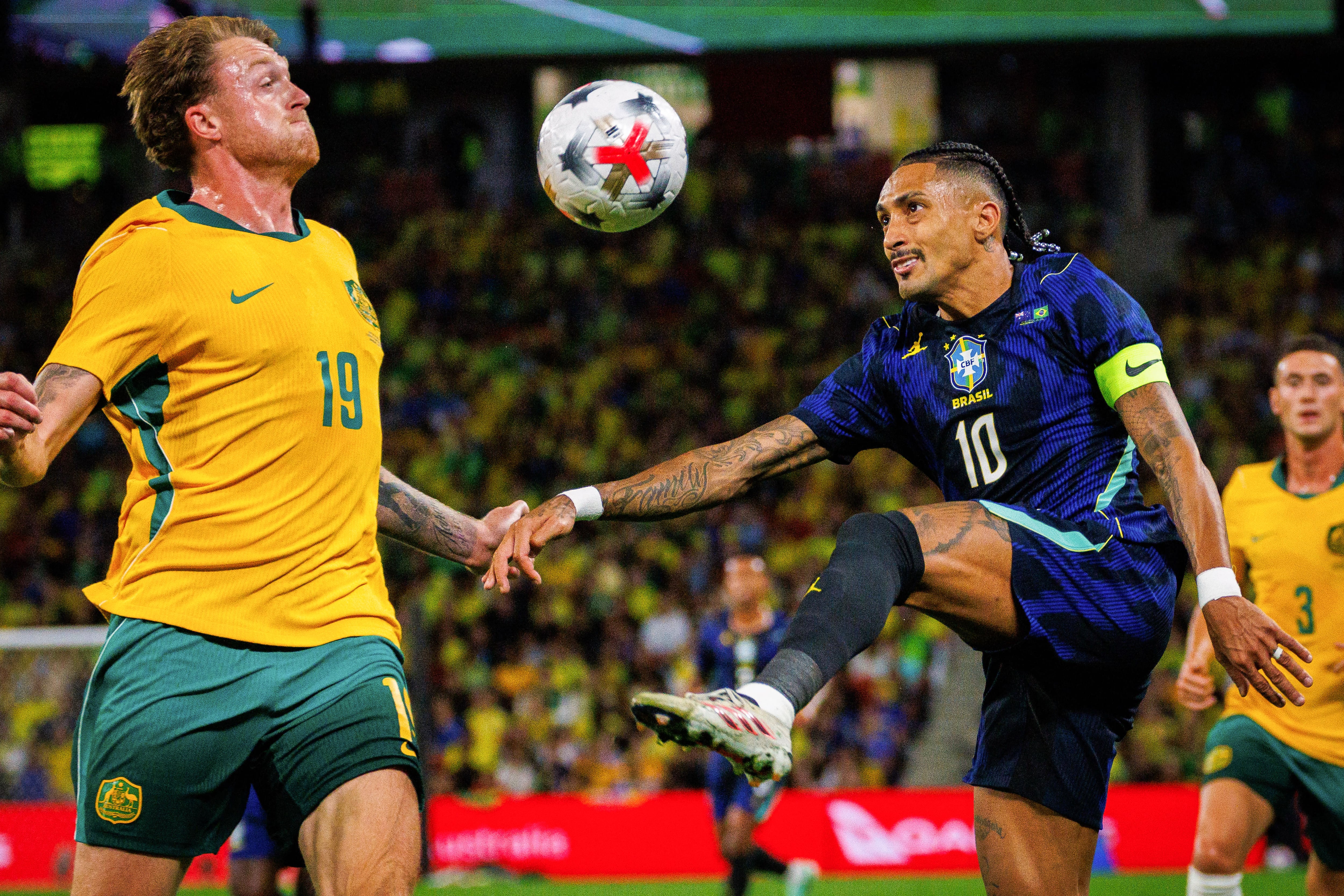 El delantero de Brasil Raphinha enfrenta al australiano Harry Souttar, durante el partido amistoso de la Fecha FIFA este 29 se setiembre en el Suncorp Stadium de Brisbane.