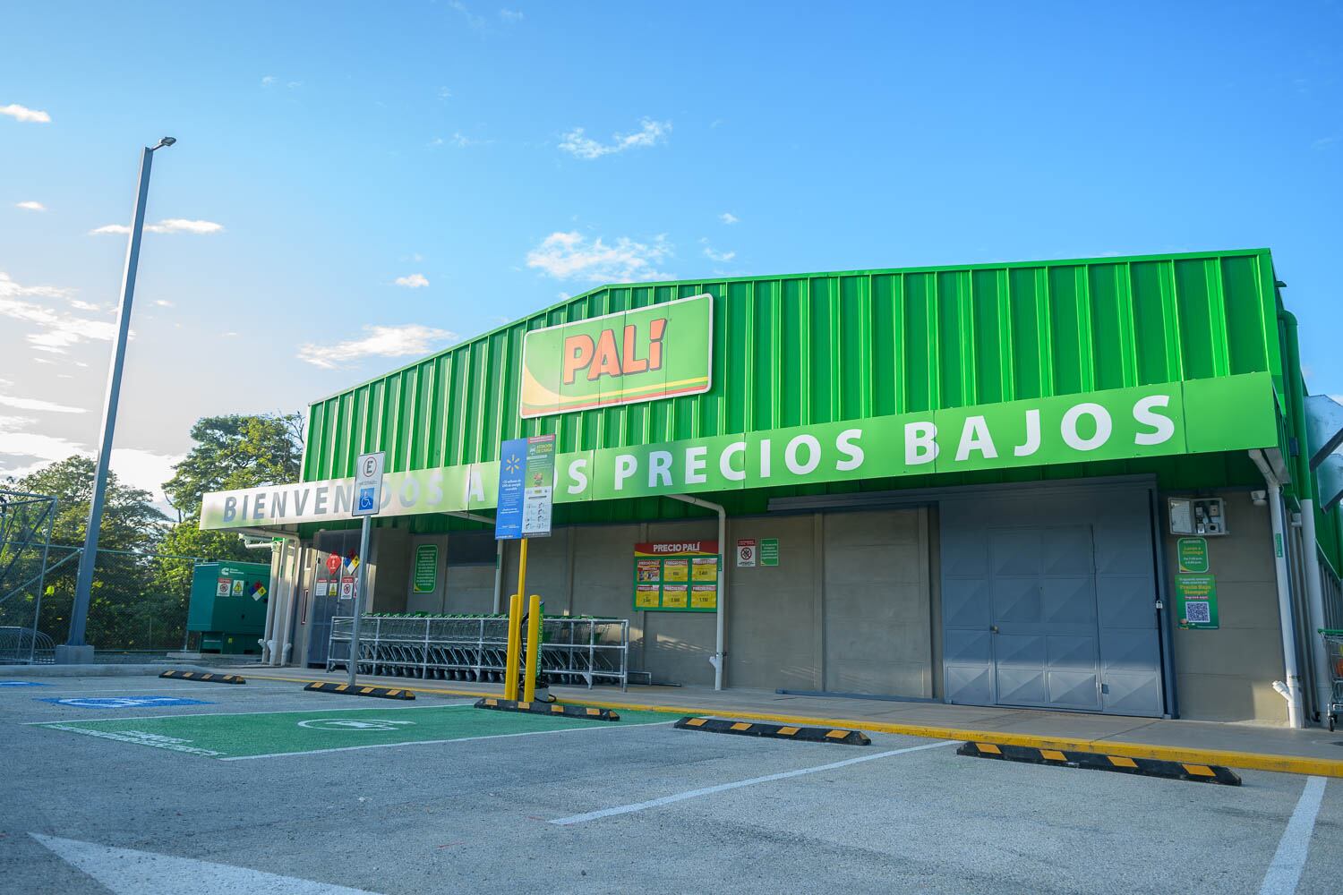 Fachada del nuevo supermercado Palí en Ciudad Cortés, Costa Rica, con estructura verde y letrero que dice "Bienvenidos a los precios bajos".